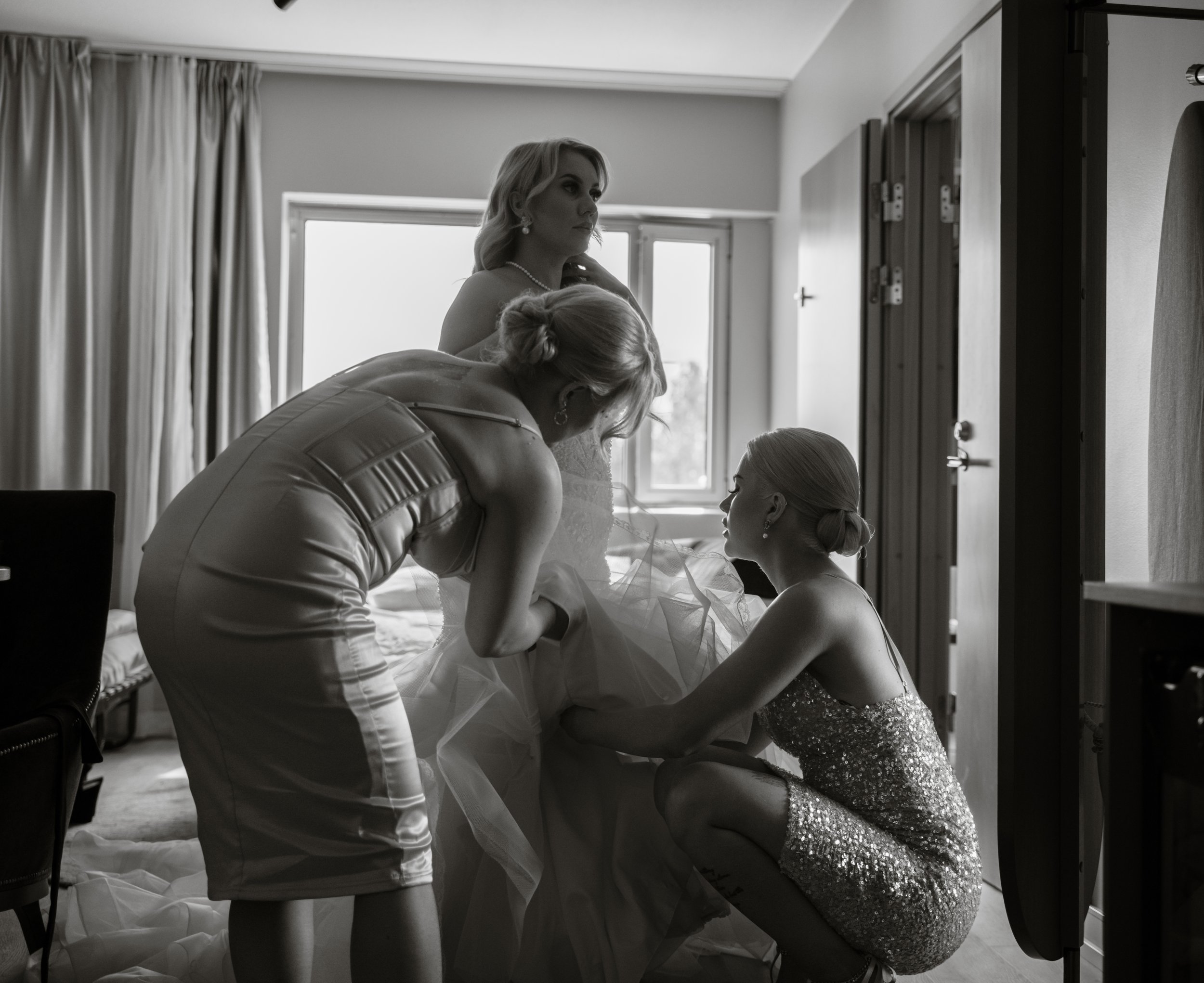 Bridesmaids helping bride with wedding dress