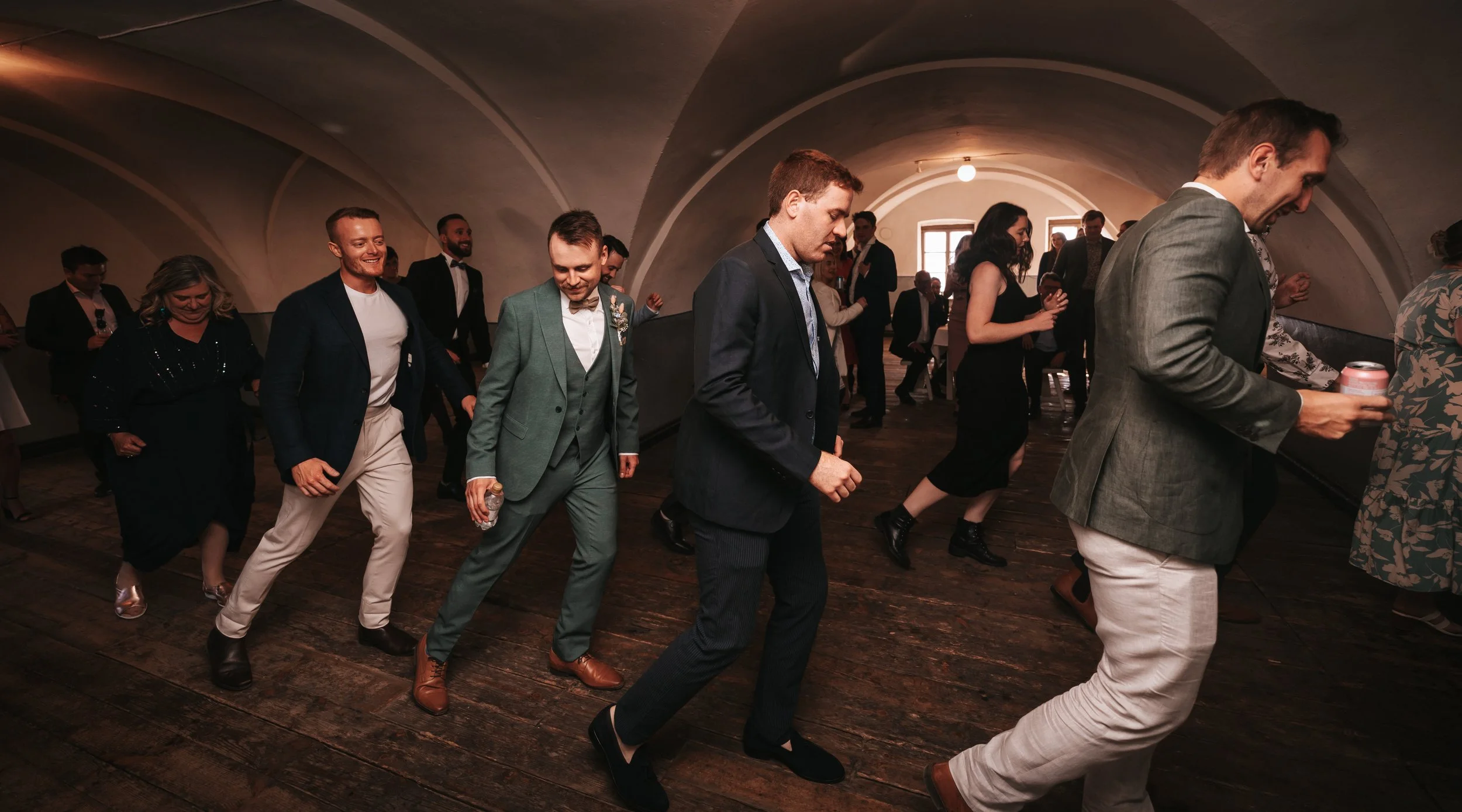 Group of people dancing indoors at a formal event.