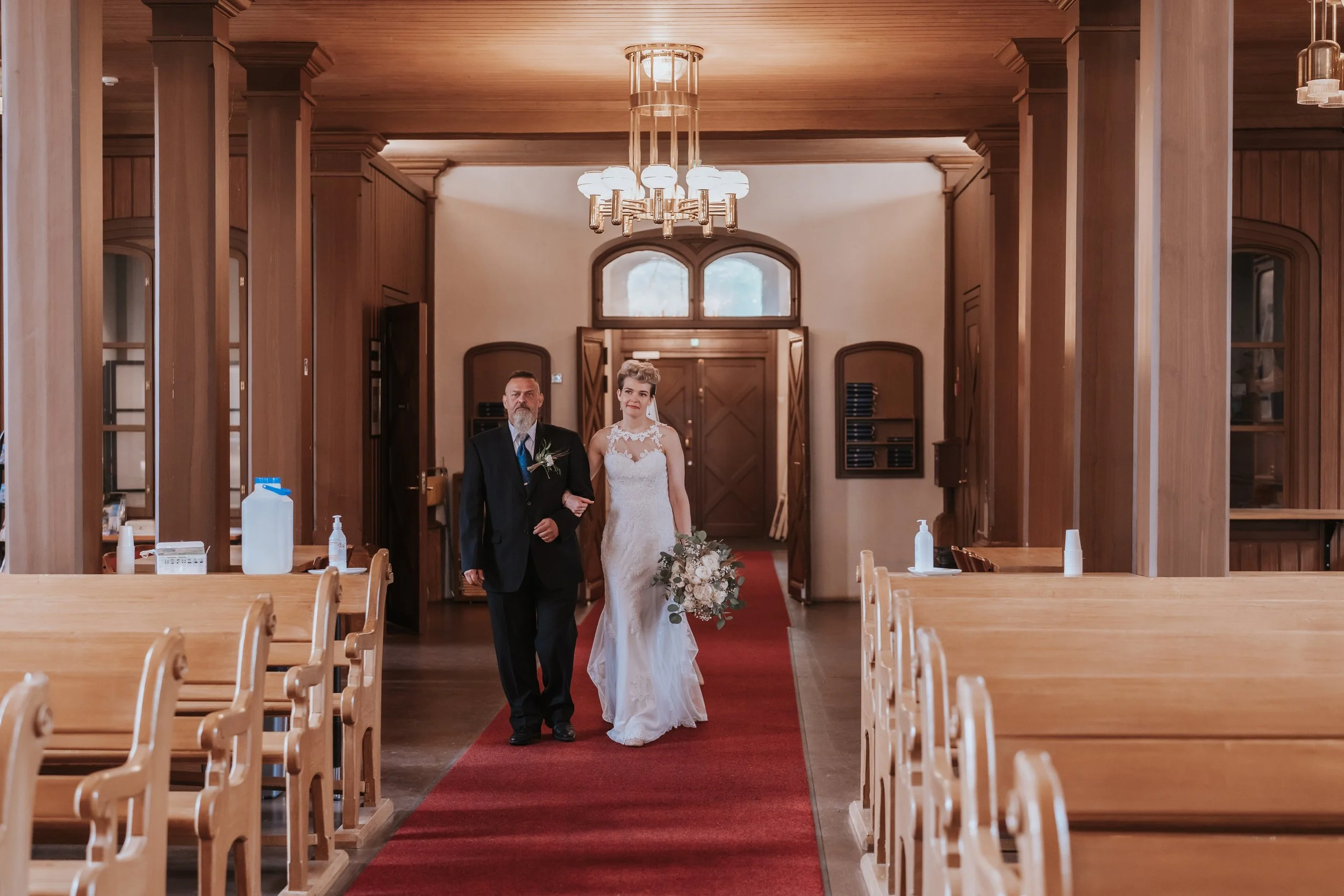 Bride walking down aisle with father in church wedding ceremony