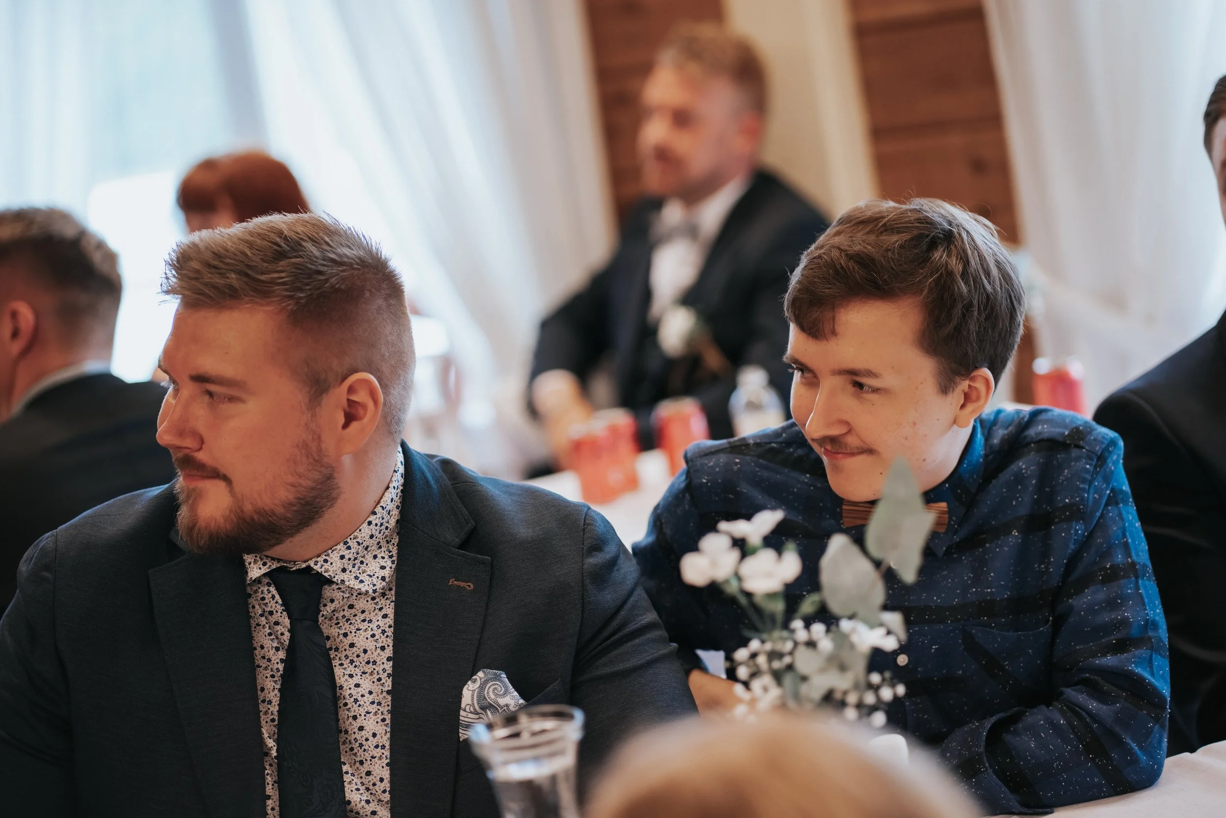 People sitting at a table during a gathering, floral centerpiece