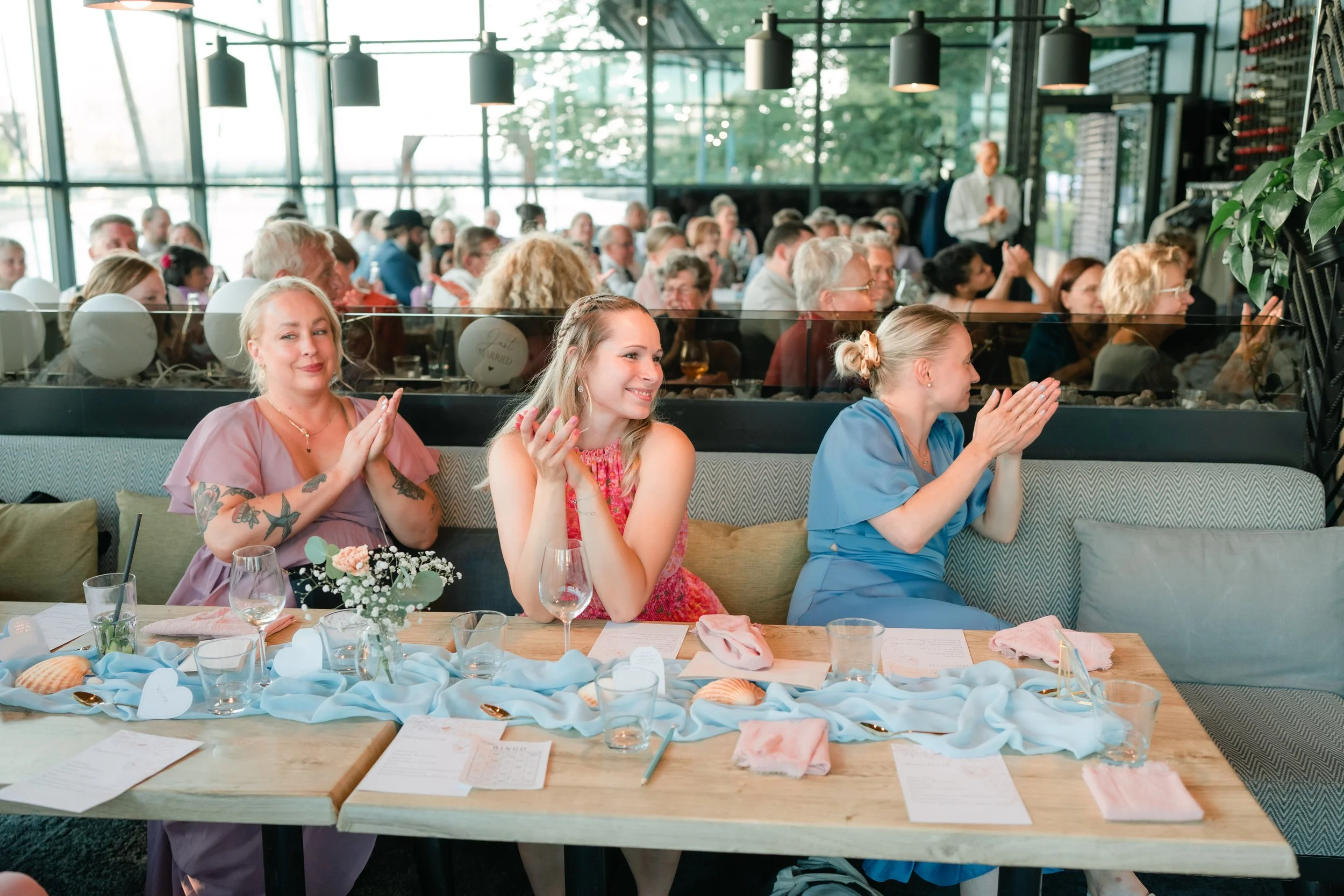 People clapping at an event with decorated tables.
