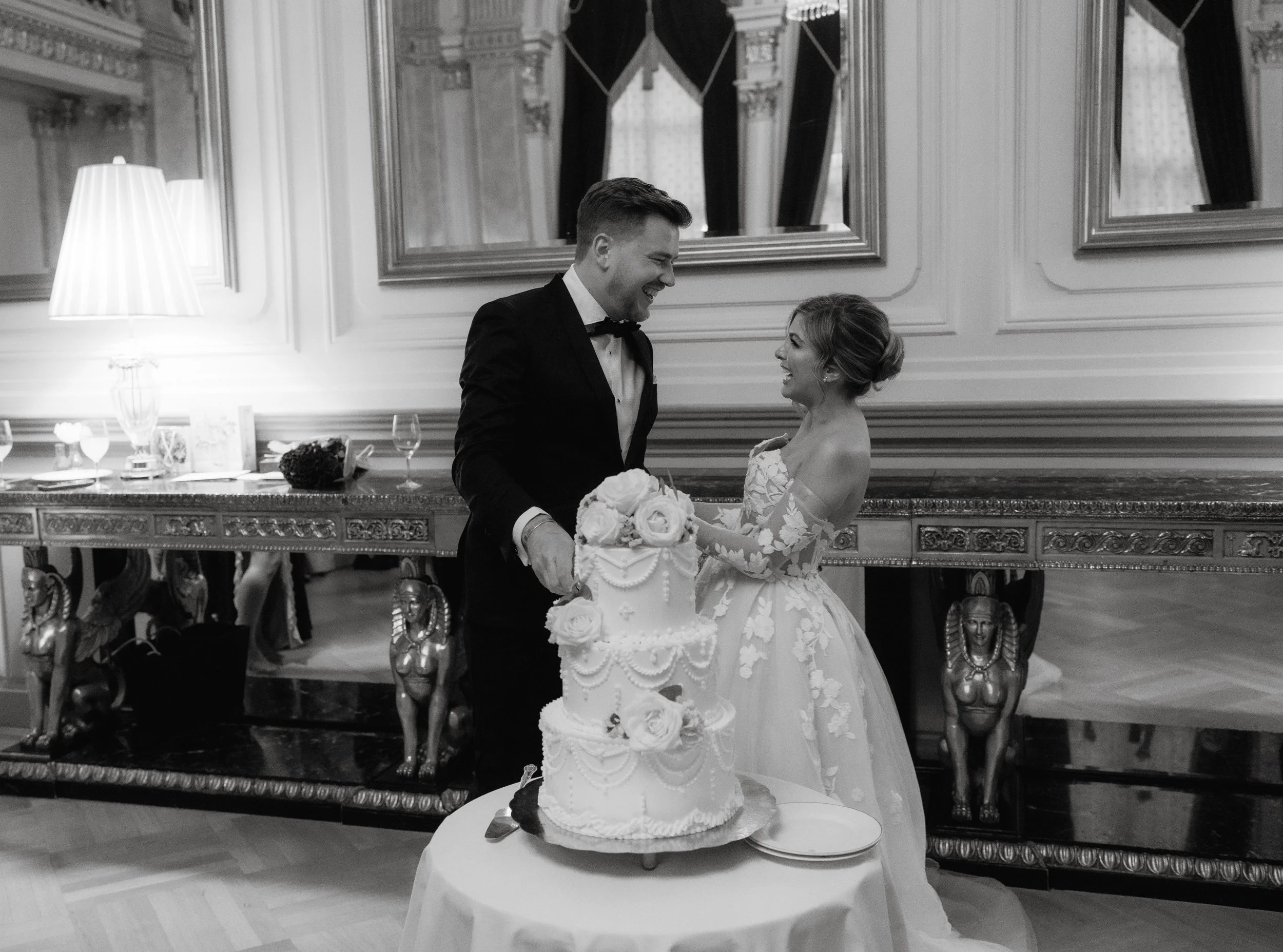 Bride and groom cutting a wedding cake in an elegant venue.