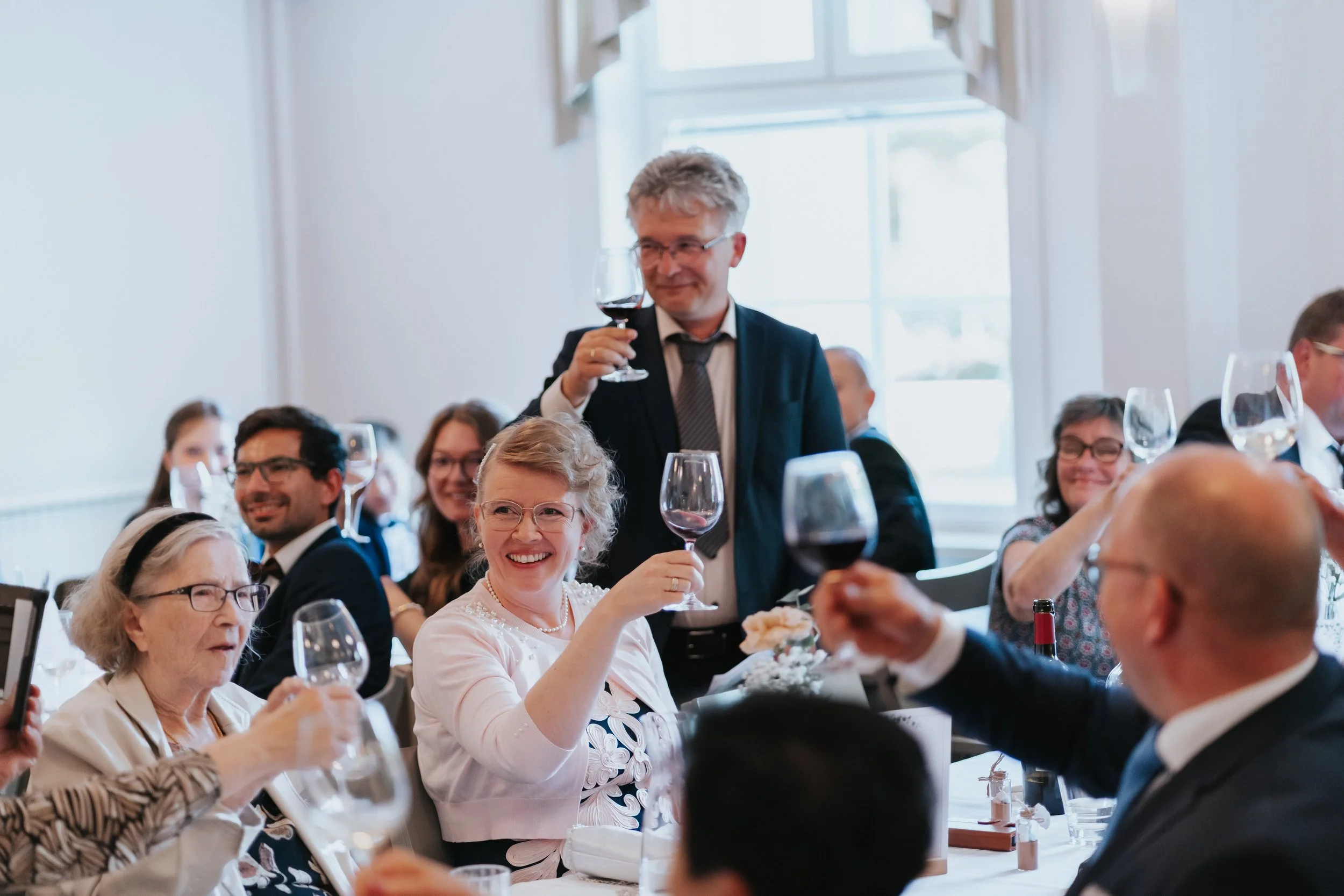 Group of people toasting at a formal event with wine glasses
