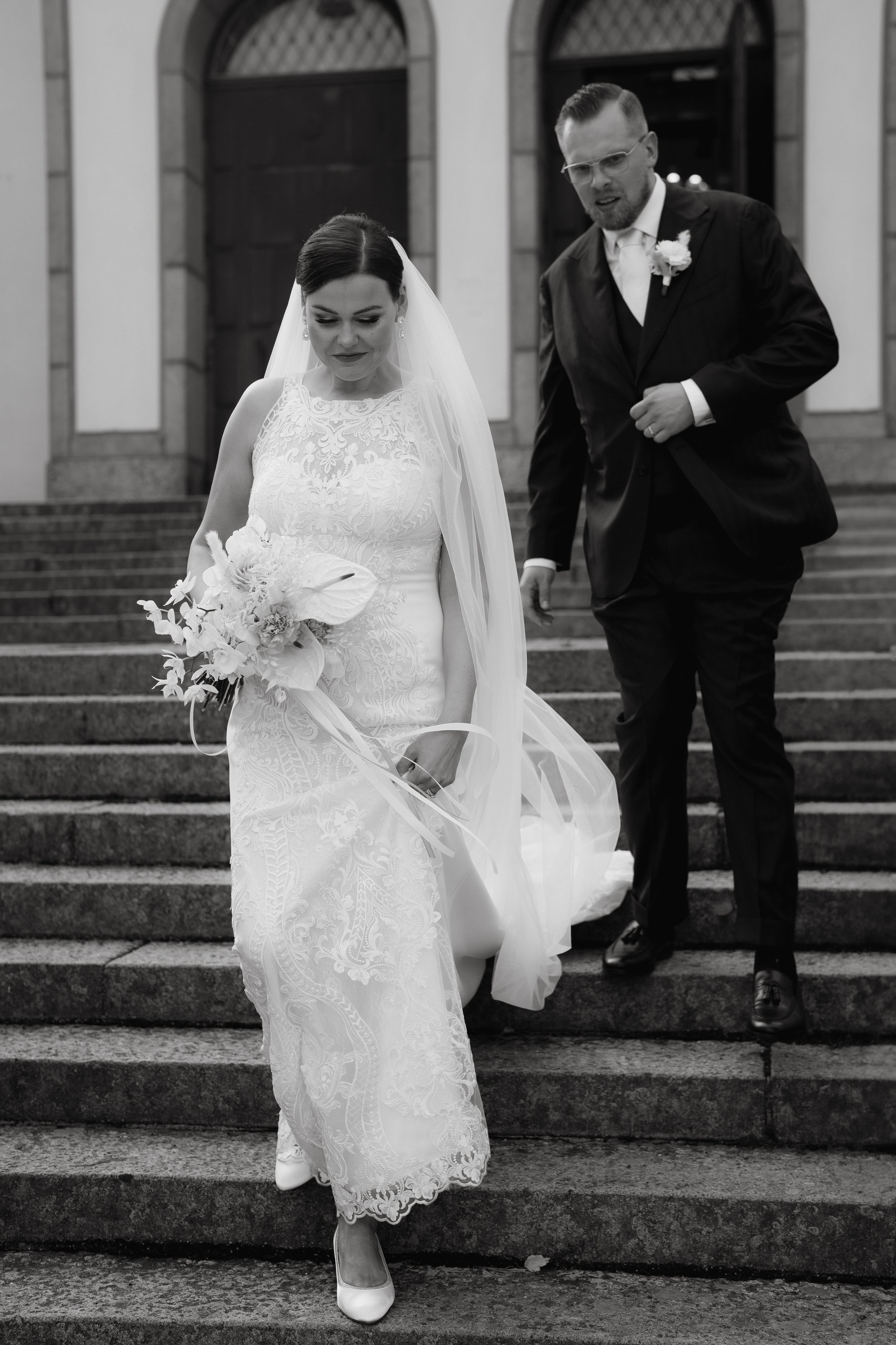 Bride and groom in wedding attire walking down steps
