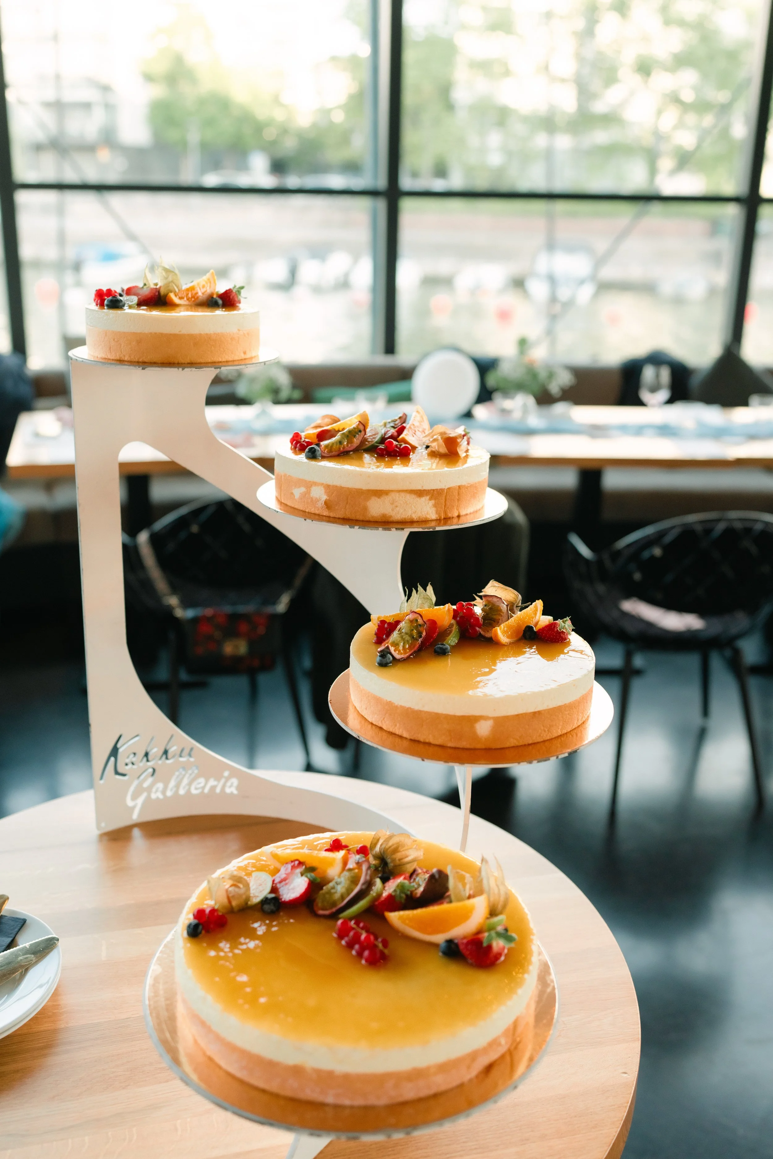 Three-tiered dessert display with cakes topped with fruits.