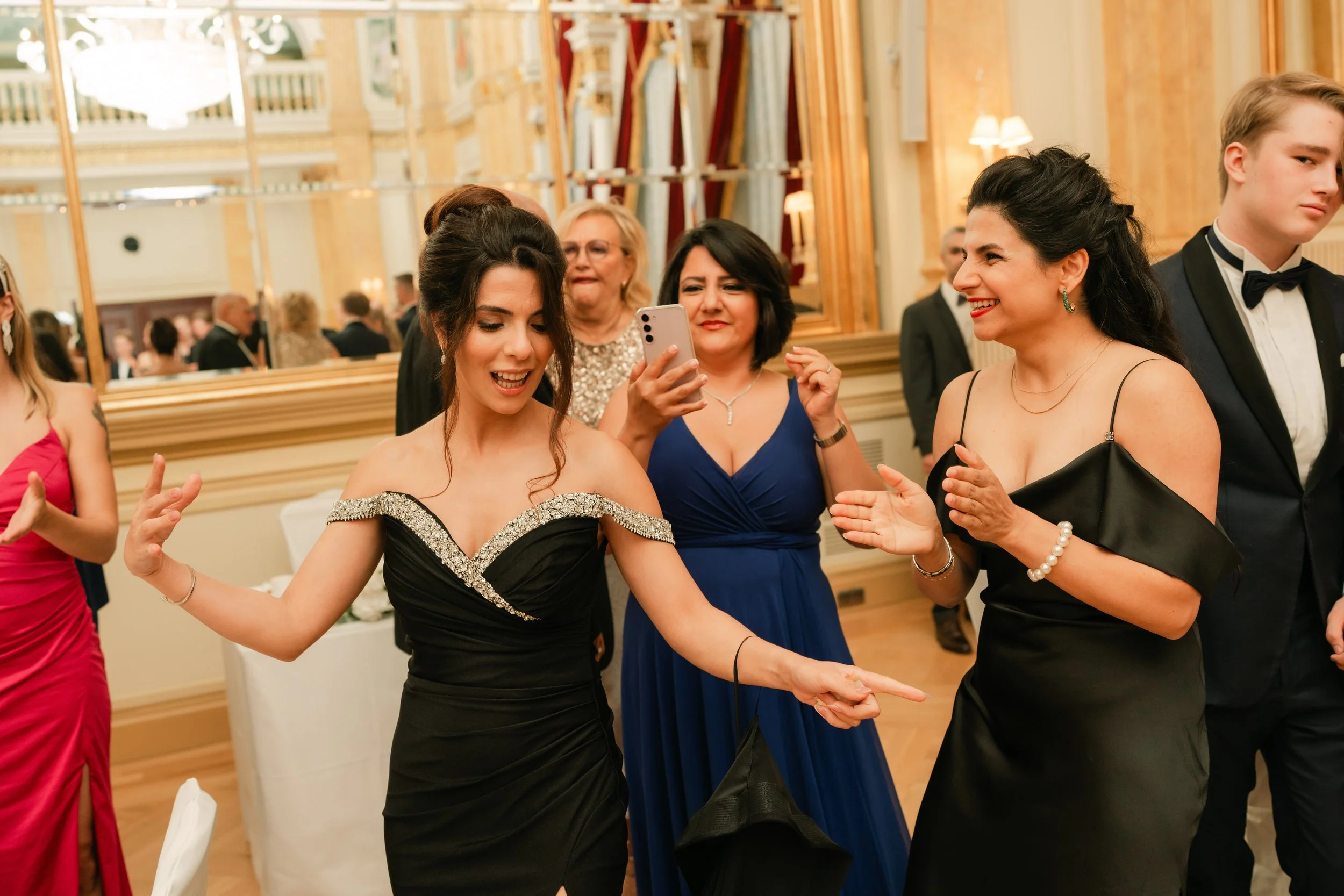 Group of people in formal attire dancing and smiling at an elegant event.
