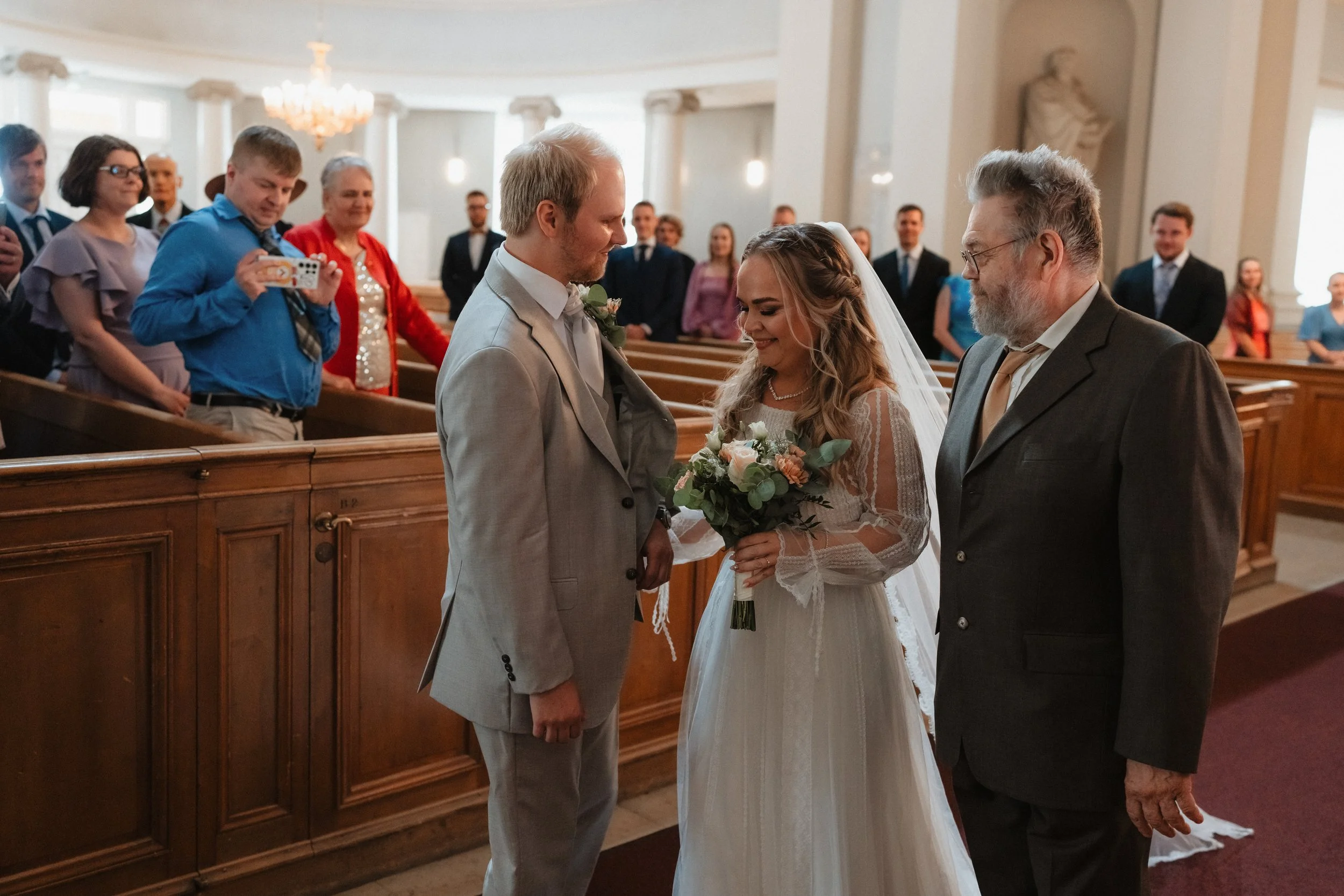 Bride and groom at a wedding ceremony with guests in church.