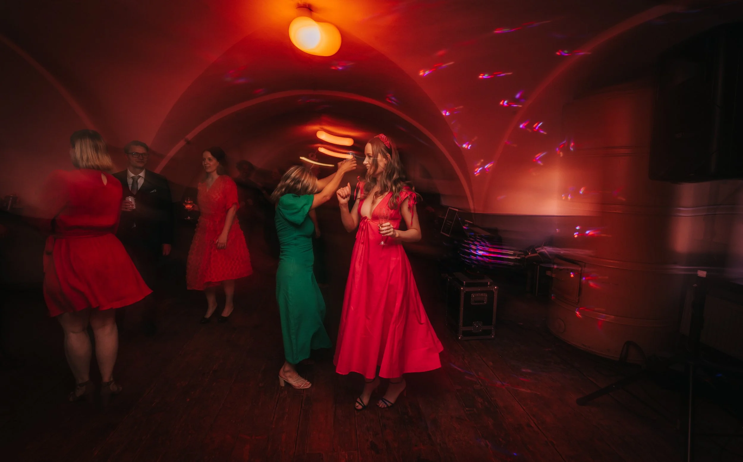 People dancing in a dimly lit room with colorful lights.