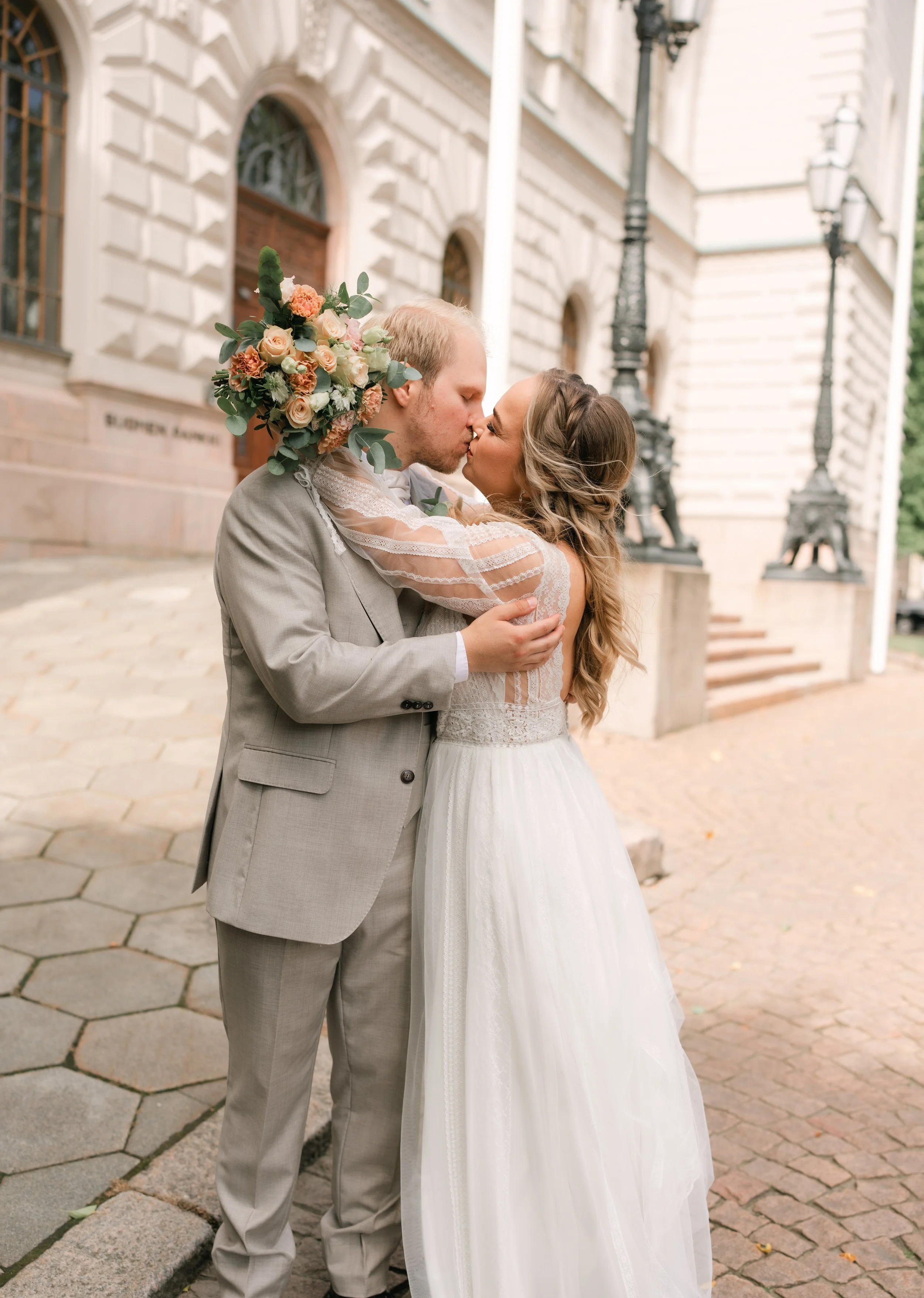Bride and groom kissing outside a historic building.