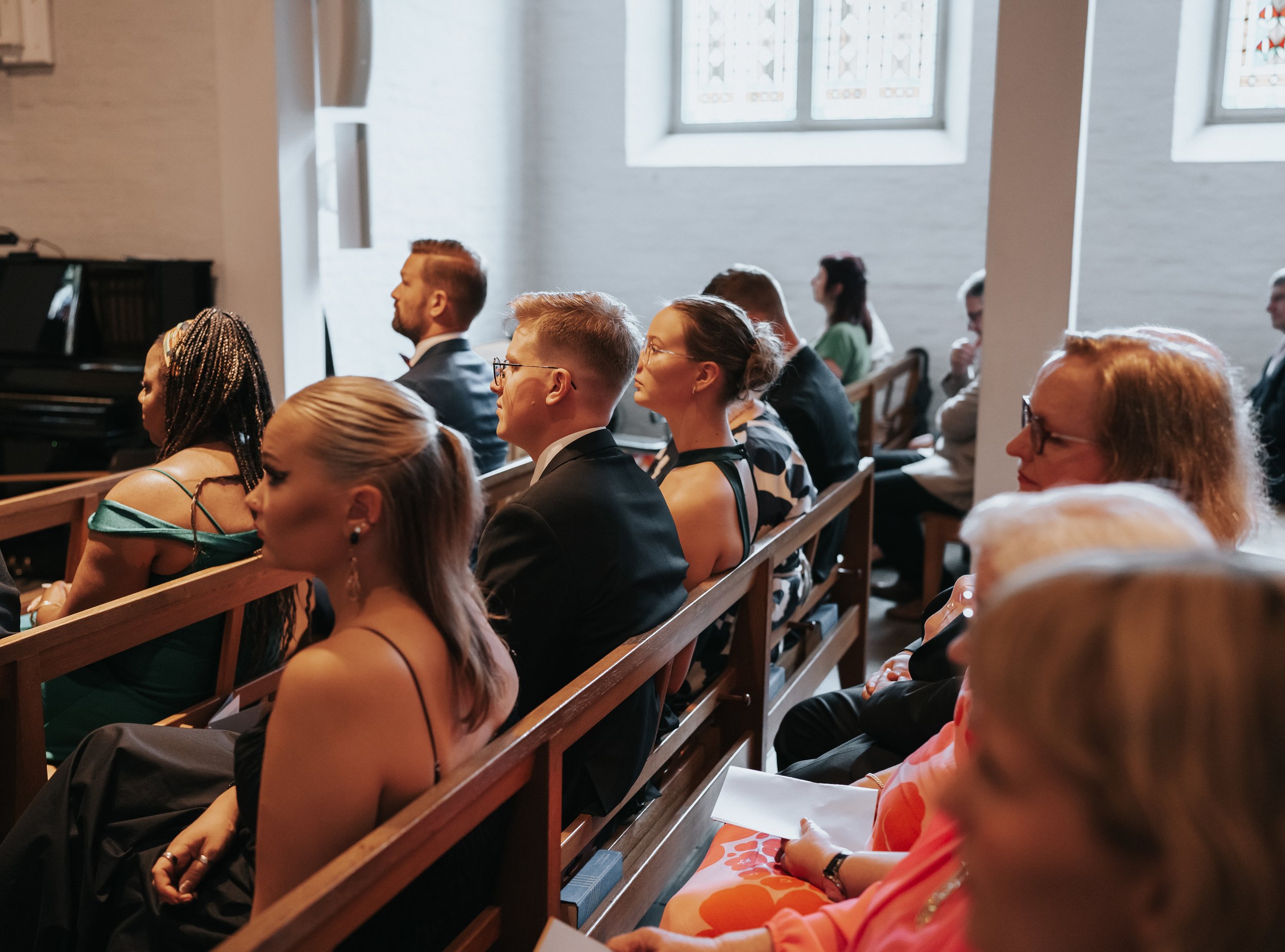 People seated in a church, dressed formally, attending an event.