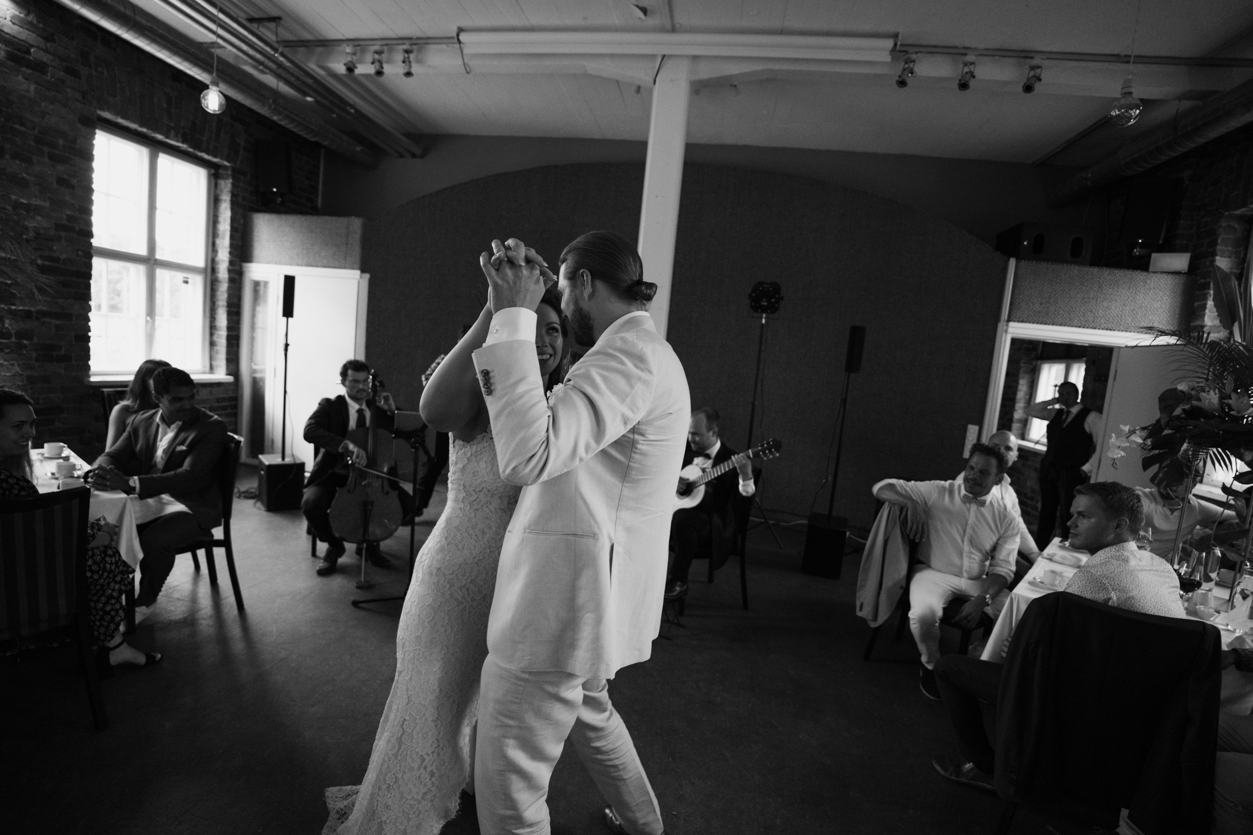 Bride and groom dancing at wedding reception with live musicians and seated guests