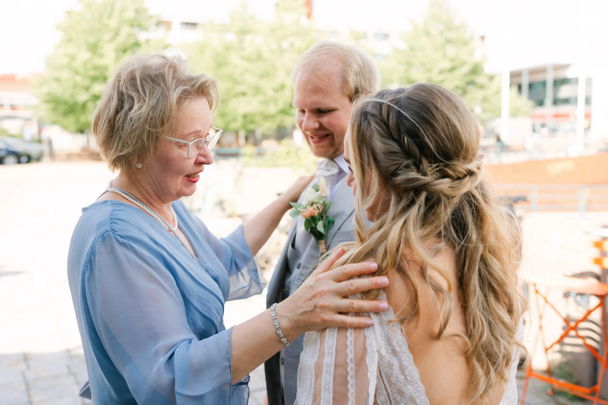 Woman in blue dress congratulating newlyweds outdoors