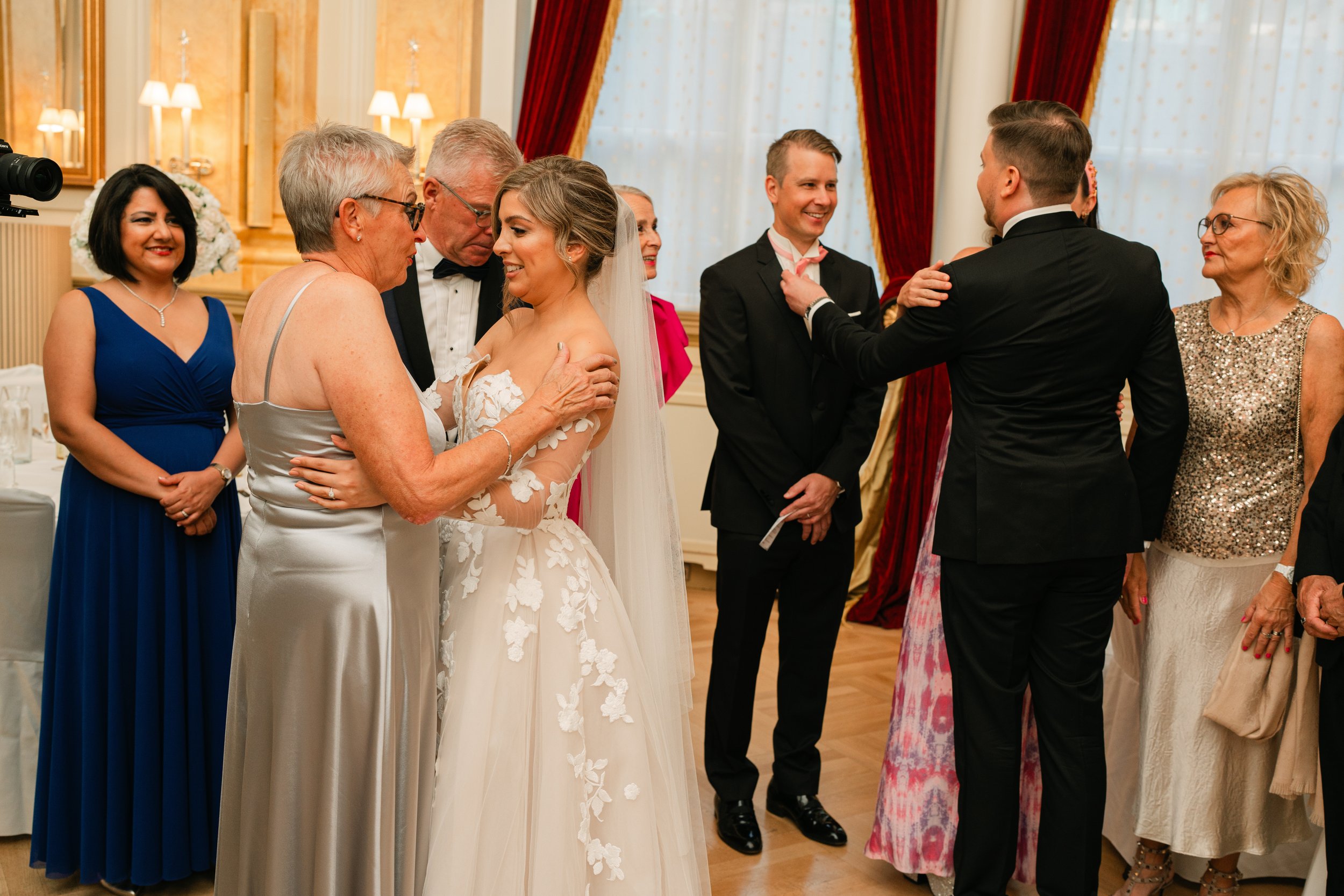 Wedding reception with people dressed formally, a bride in a white gown, and guests interacting, indoors with elegant decor.