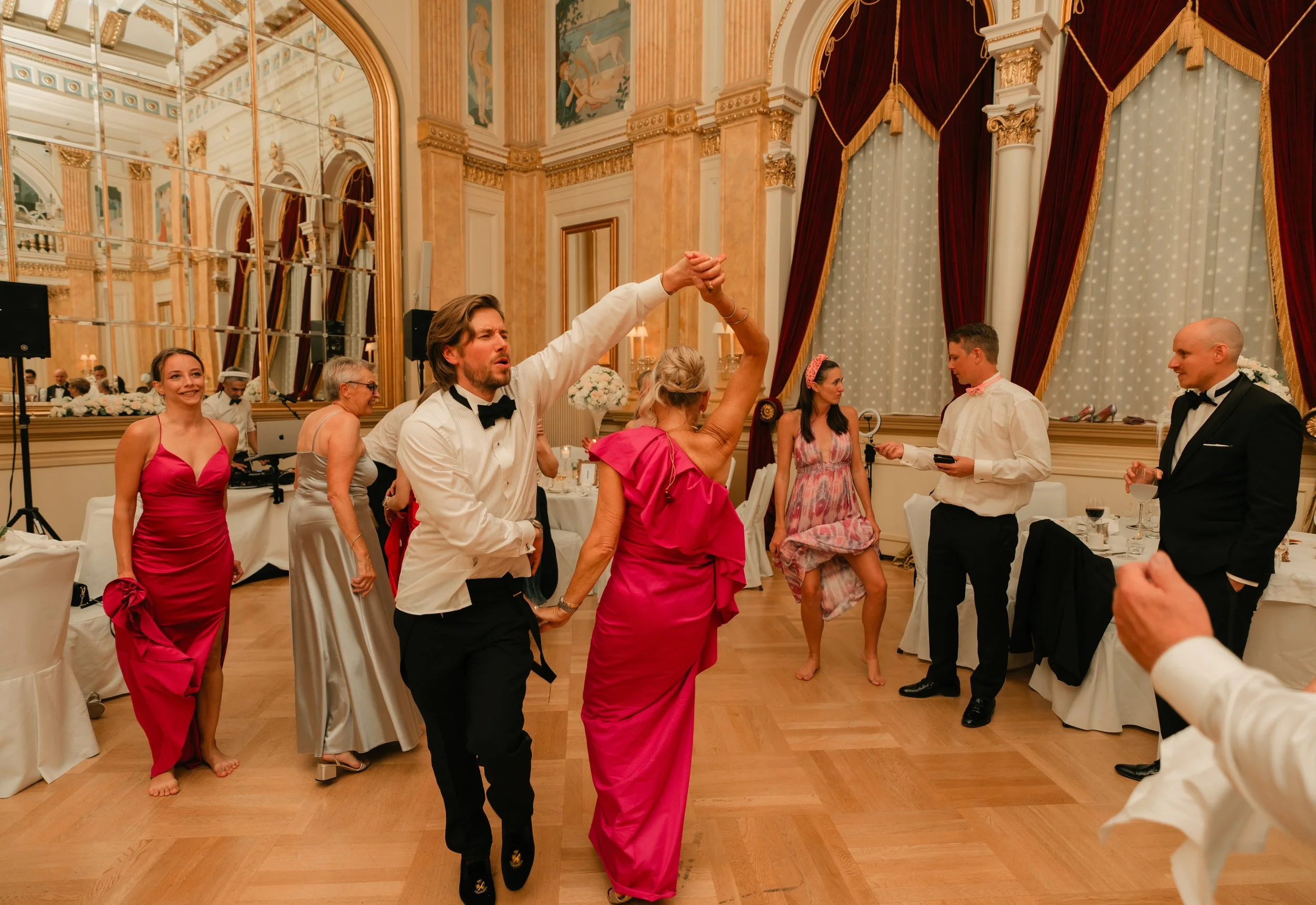 Elegant ballroom setting with people in formal attire dancing.