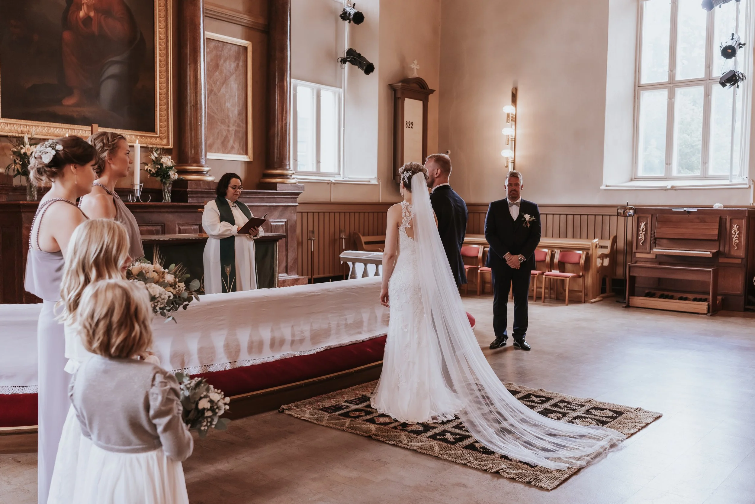 Wedding ceremony in a church with bride, groom, bridesmaids, and officiant.