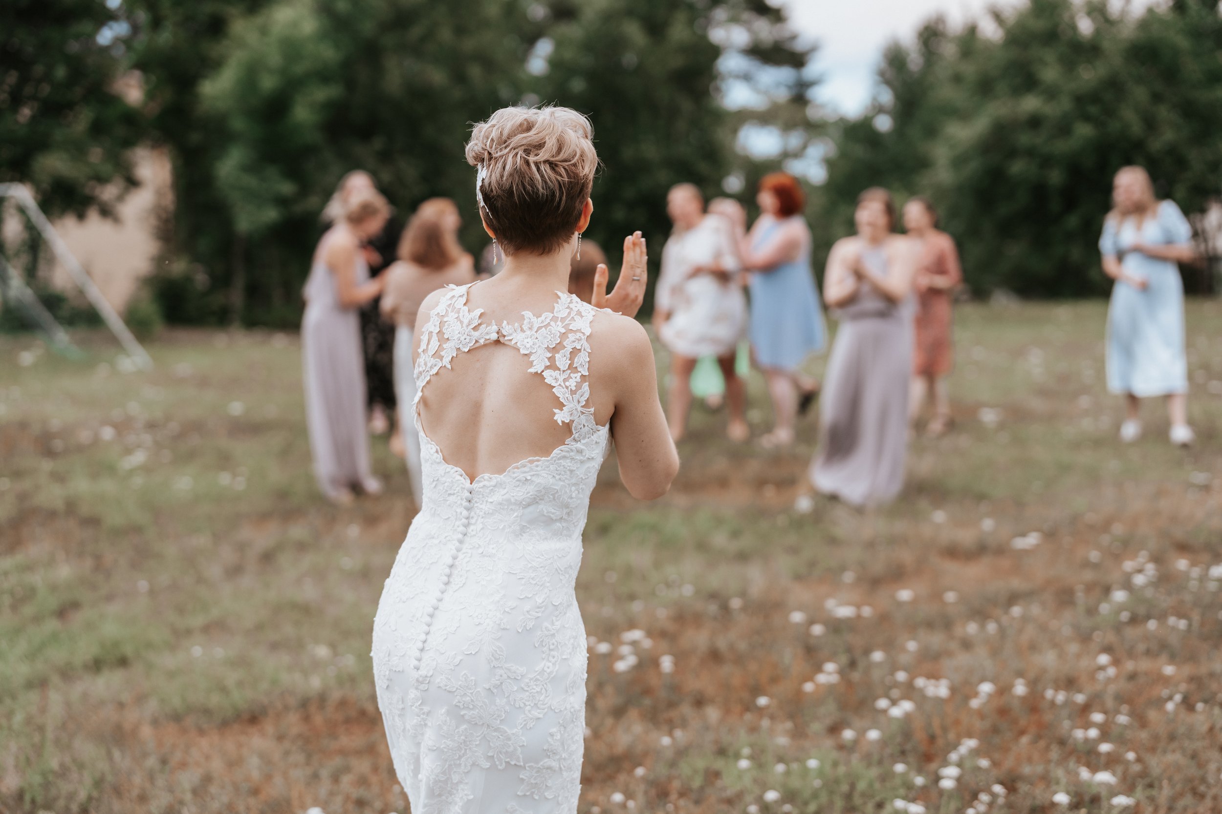 Bride in lace dress outdoors with people in background