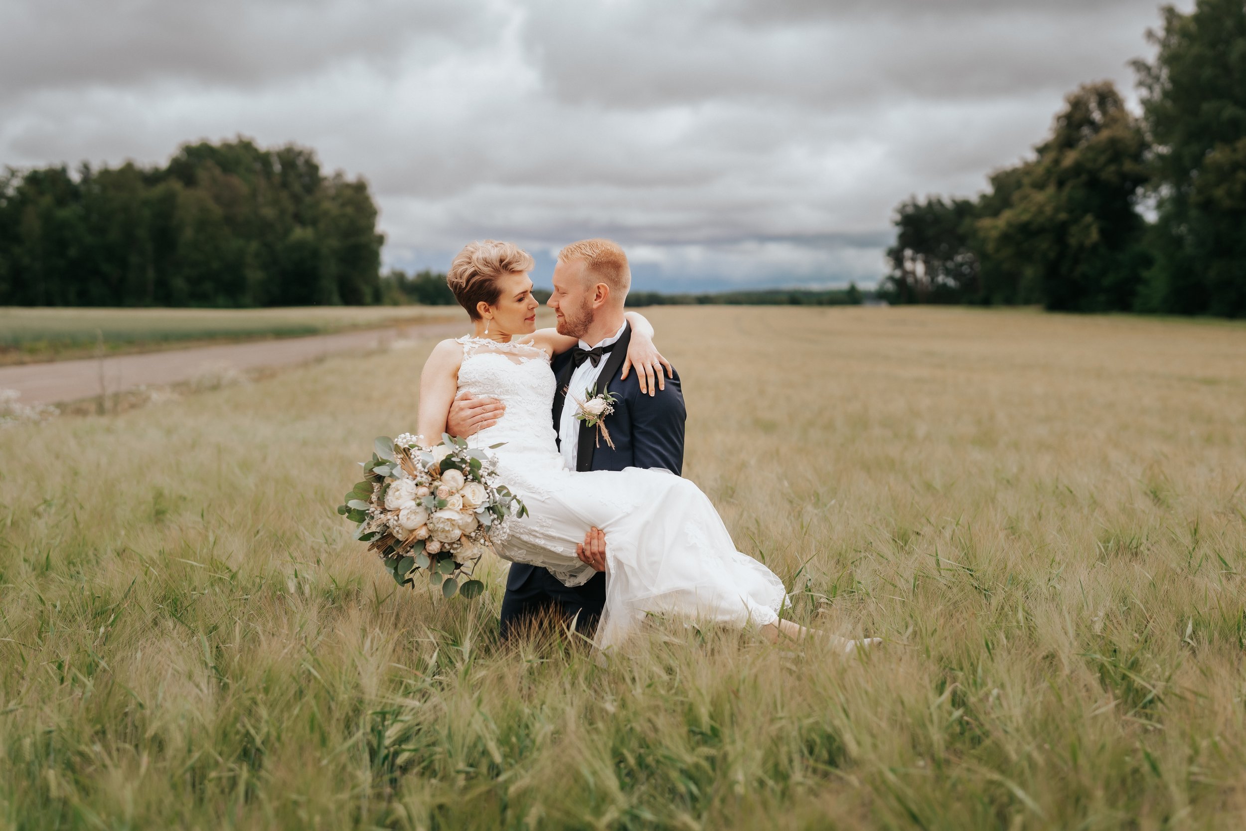 Bride and groom in field holding bouquet