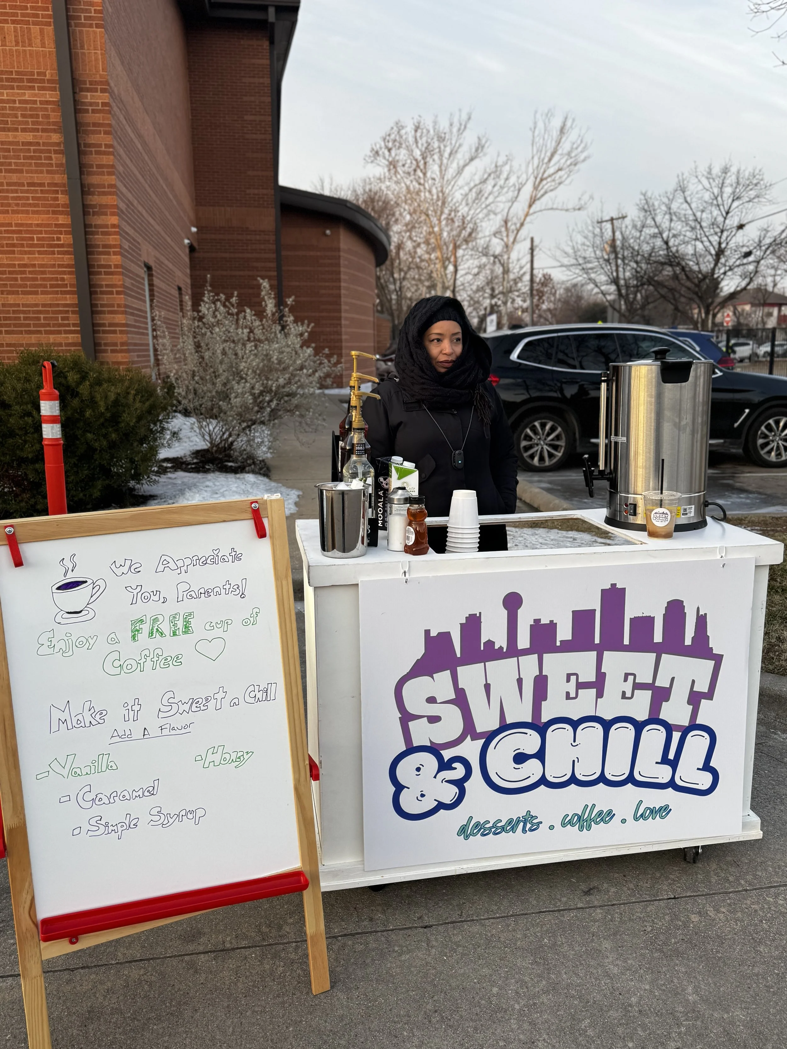 A person pouring coffee from a glass pitcher into five small glass cups arranged in a row on a table.