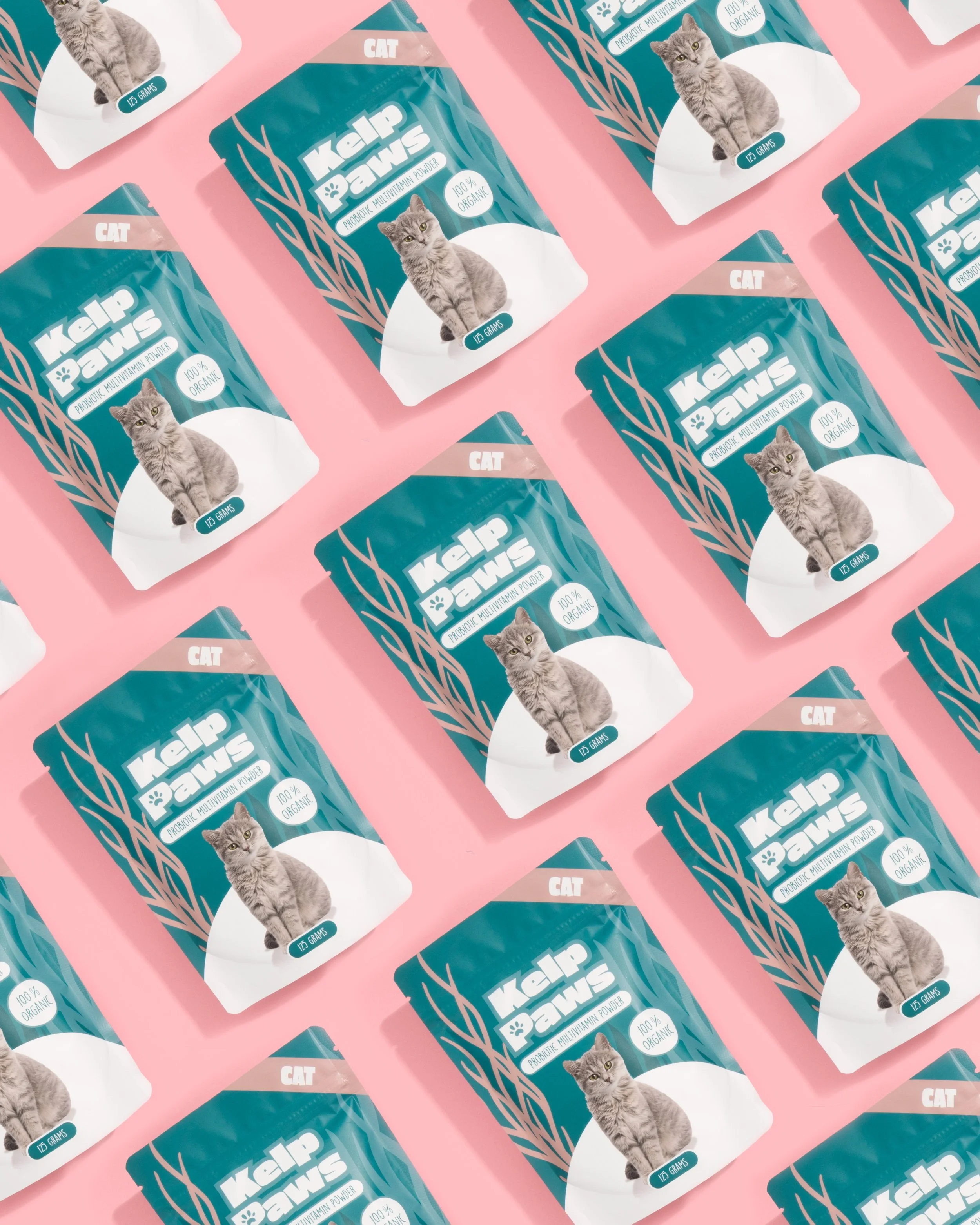 Multiple packages of Kalp Paw probiotic multivitamin powder for cats arranged in a grid pattern on a pink background, each package featuring a gray cat sitting and the text indicating the product is 125 grams, 100% organic.
