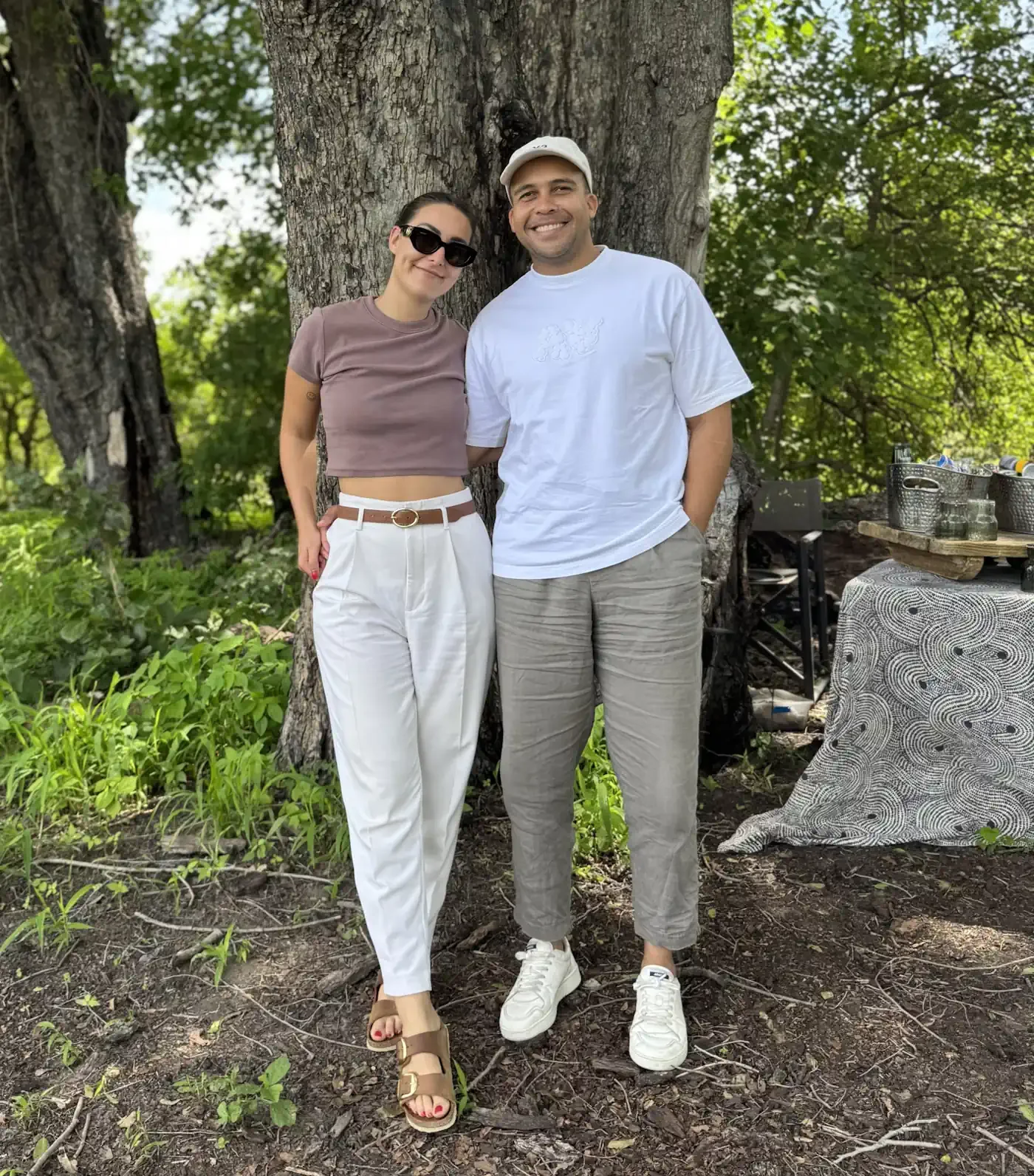 James and Kristy, the husband-and-wife founders of Beyond the Baobab, standing together under a tree near a luxury safari setup in Botswana.