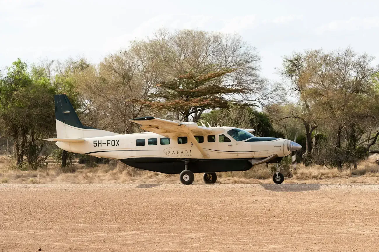 A small light aircraft parked on a remote dirt airstrip in the bush for a luxury African fly-in safari