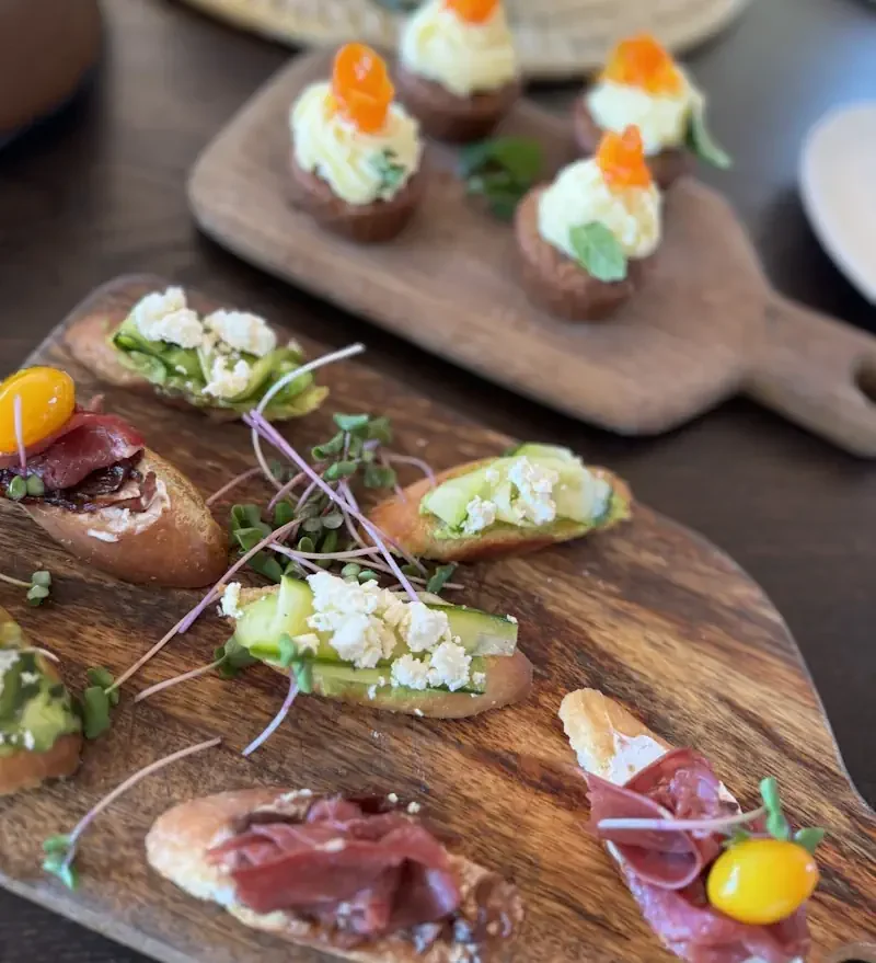A close-up of beautifully crafted gourmet appetizers served on a rustic wooden board, showcasing the exceptional culinary experience at a luxury safari camp.