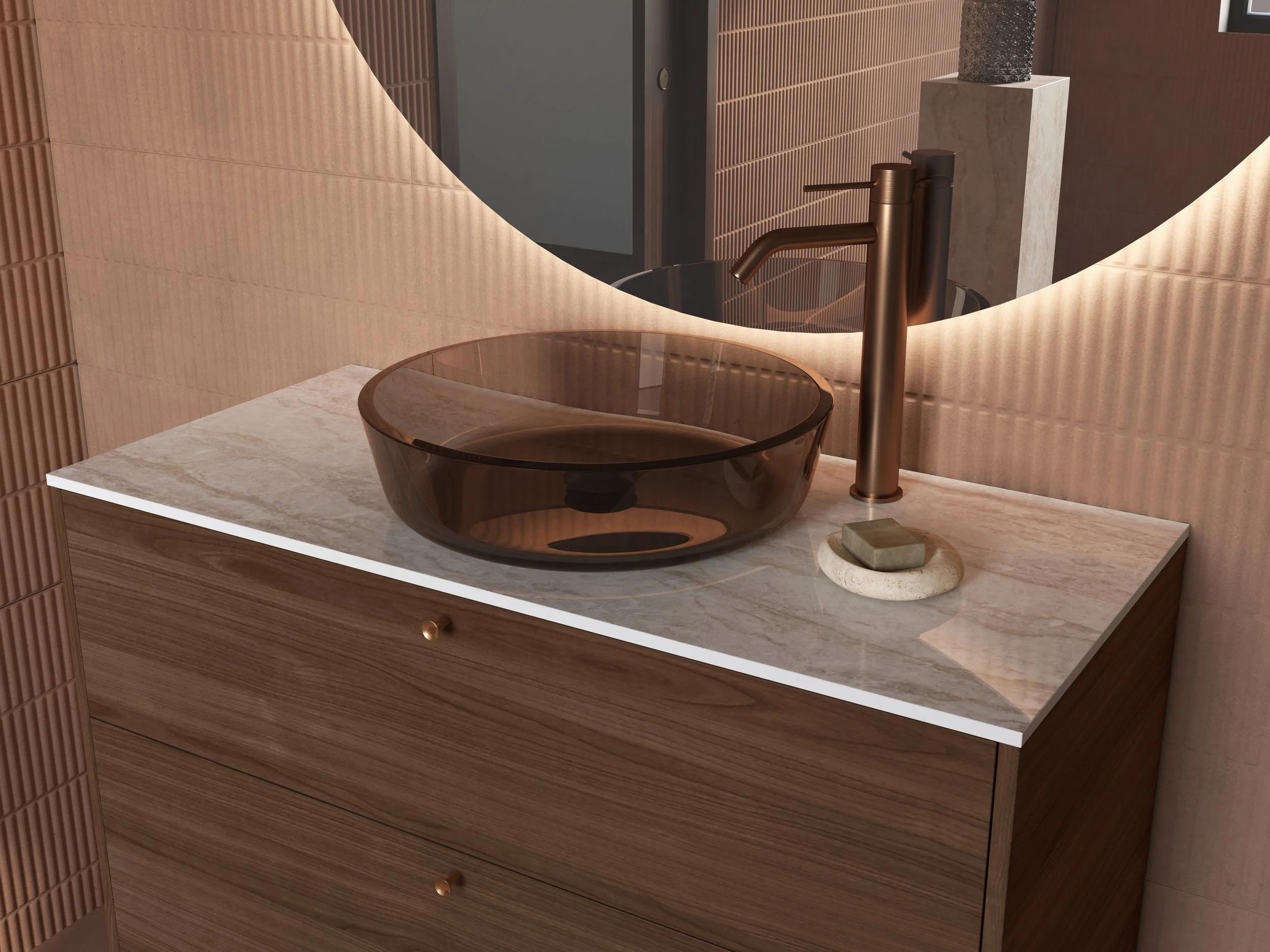 Et badeværelsesbord med en brun gennemsigtig vask og en bronzefarvet armatur, en lille sten, og en dekorativ vasestatuette. Baggrund med en rund speil og lysebrune fliser.