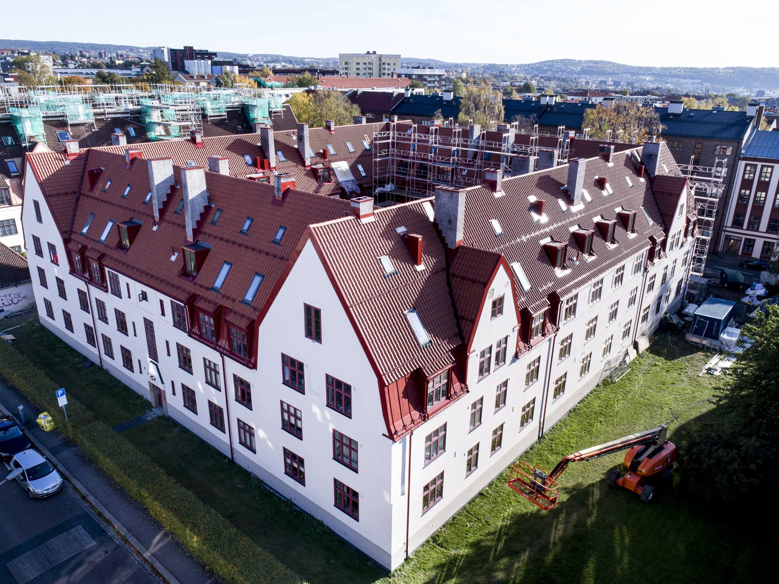 Bilder av et byggeplasser for et flatt tak på et nydelig, hvitt bygårdsbygg med rød takakt.