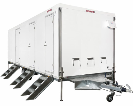 En stor, hvit luftkondisjonert trailer med flere utganger og stiger, brukt til toaletter.