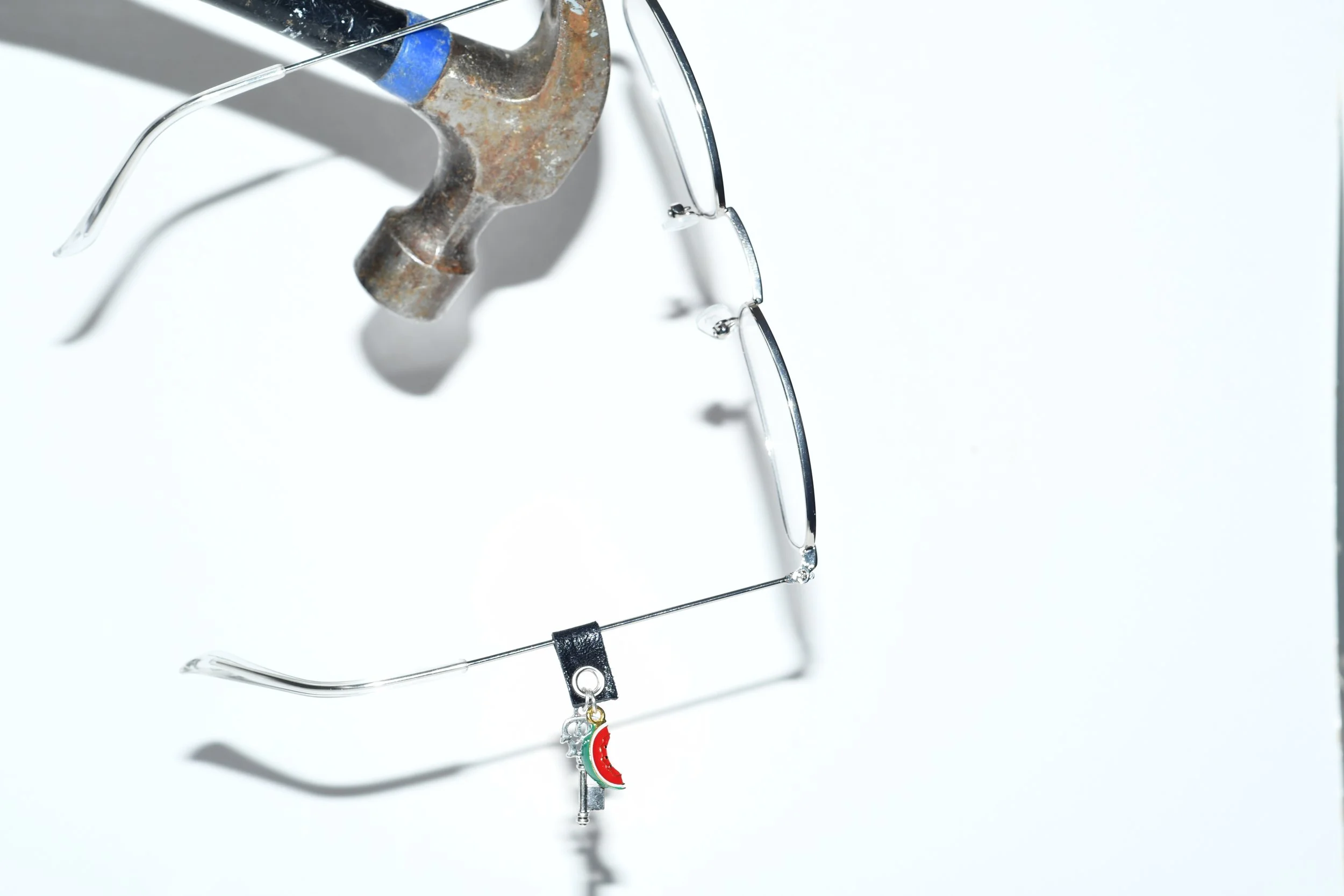 La Tâj handcrafted eyewear jewellery with leather attachment, silver key charm, and multicolour watermelon pendant on eyeglasses.