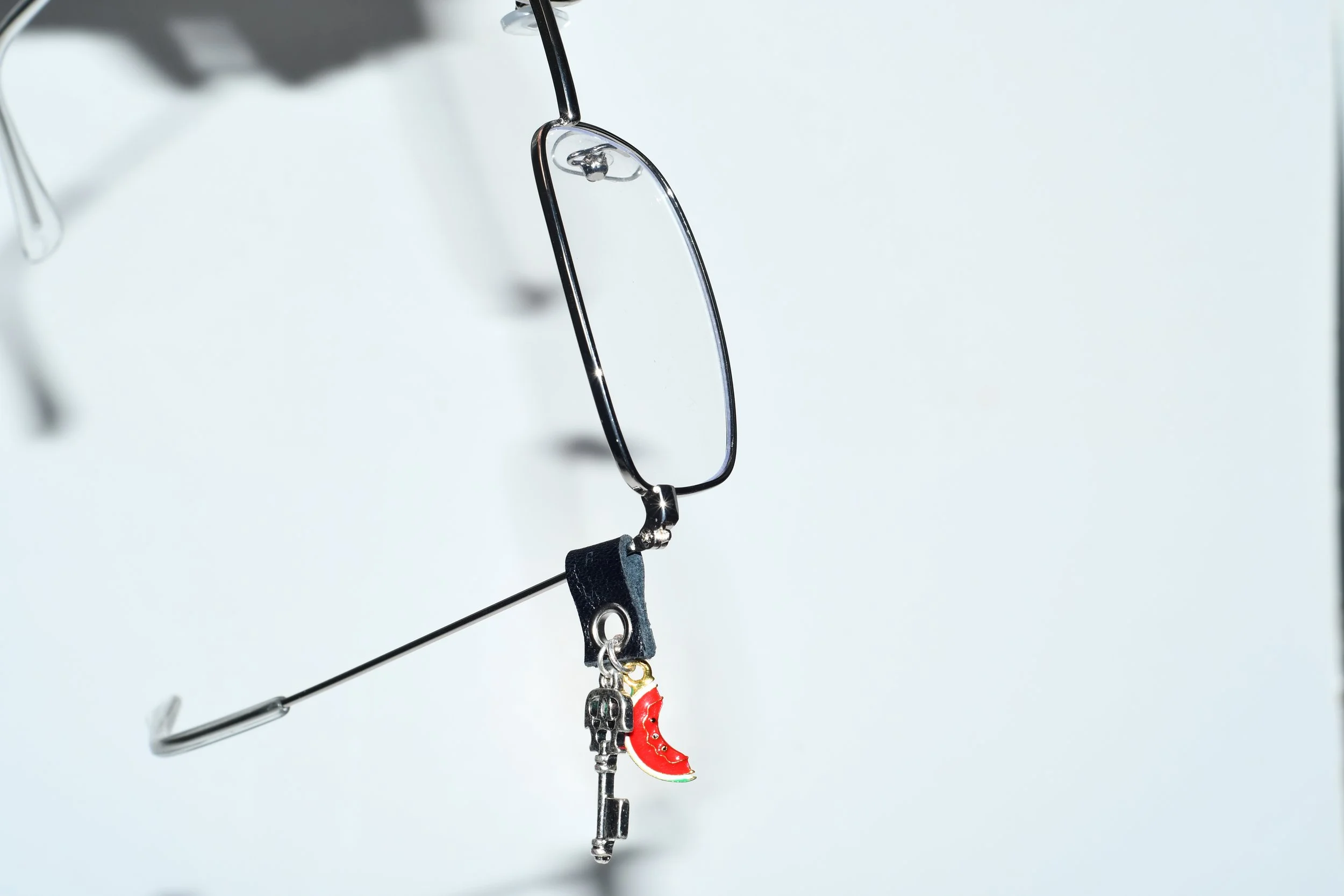 La Tâj handcrafted eyewear jewellery with leather attachment, silver key charm, and multicolour watermelon pendant on eyeglasses.