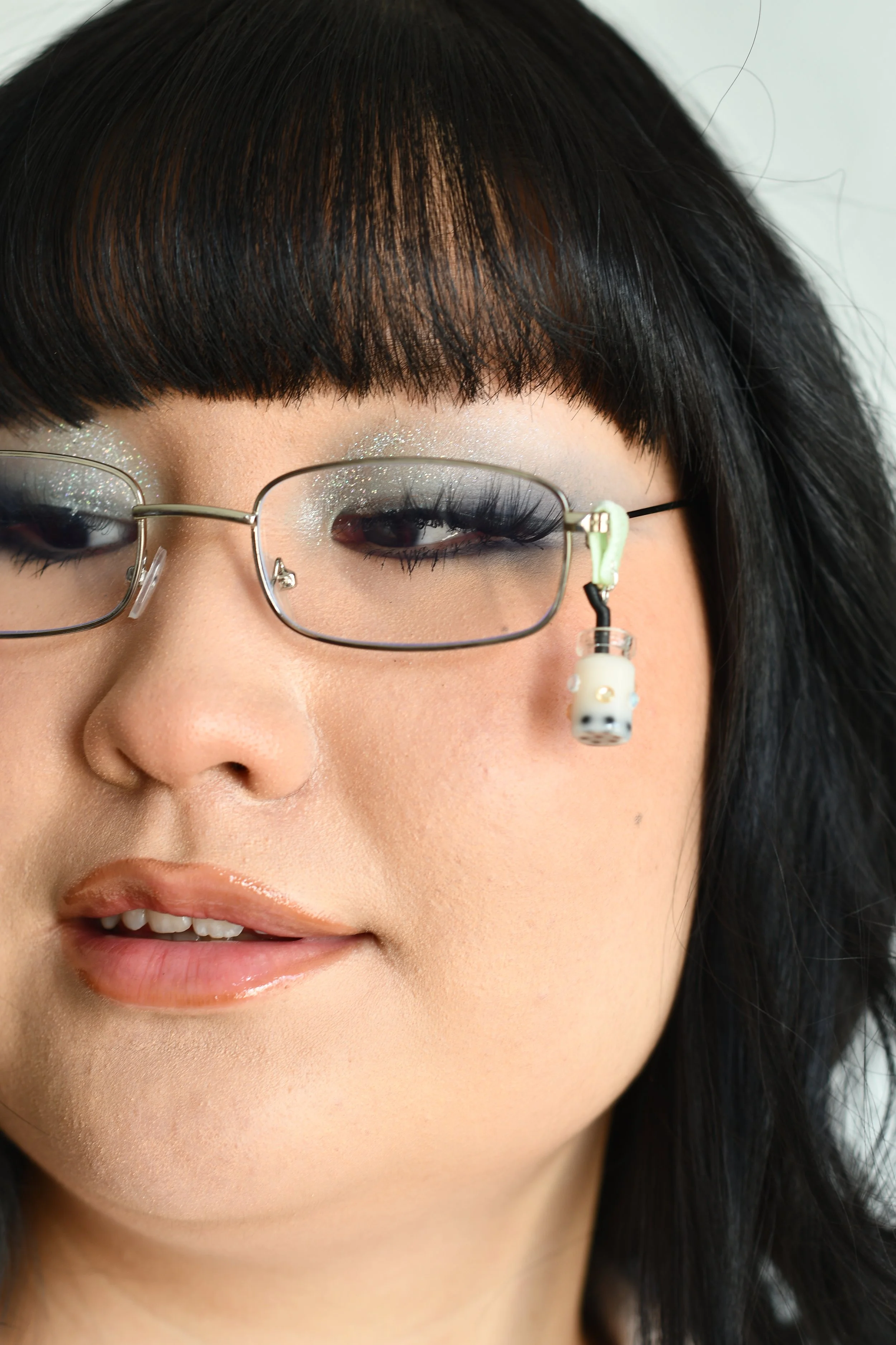 Asian girl wearing glasses with Mango Boba Tea Charm attached to mint green soft fabric with transparent and light yellow diamonds