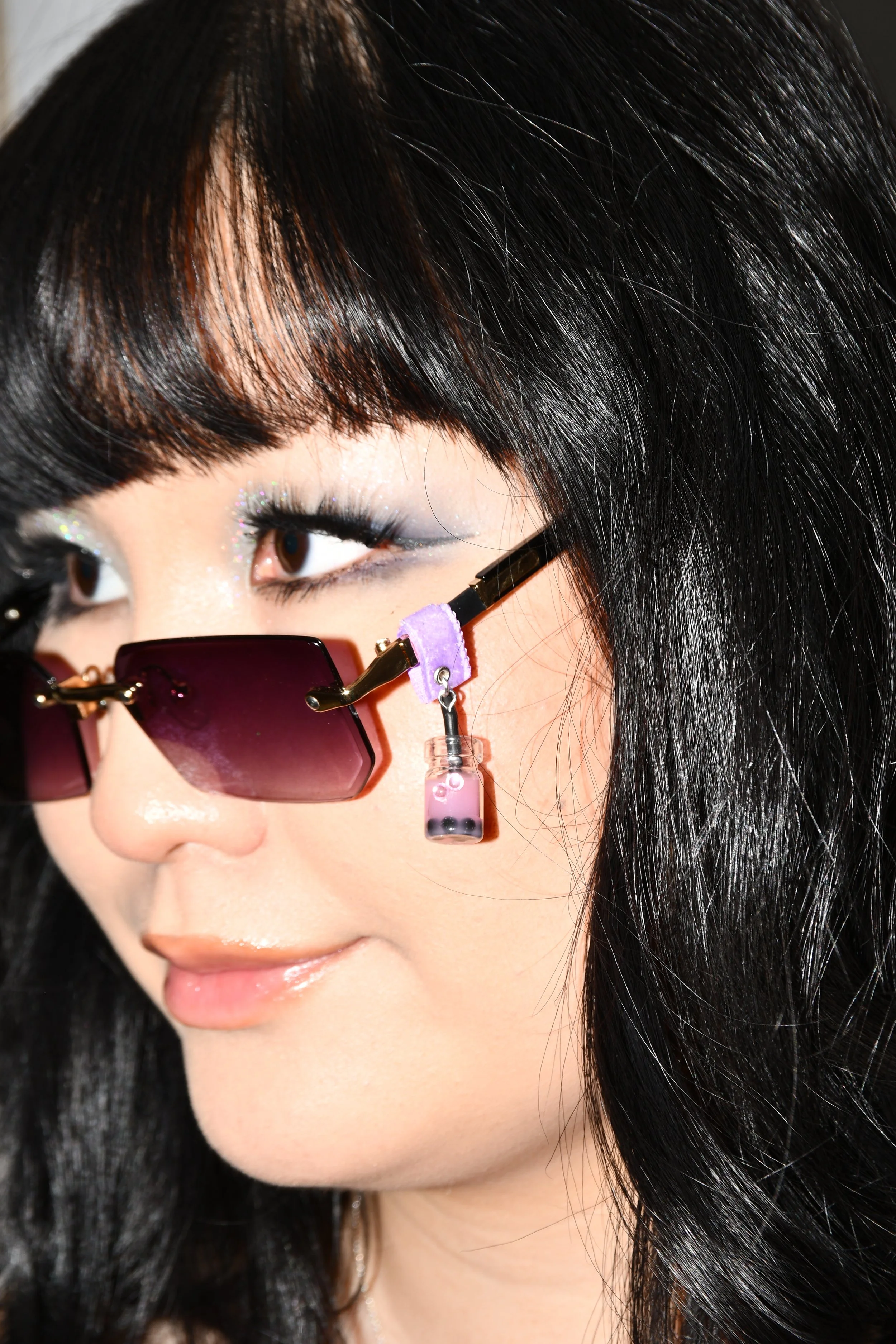 Asian girl wearing glasses with rose Boba Tea Charm attached to purple soft fabric