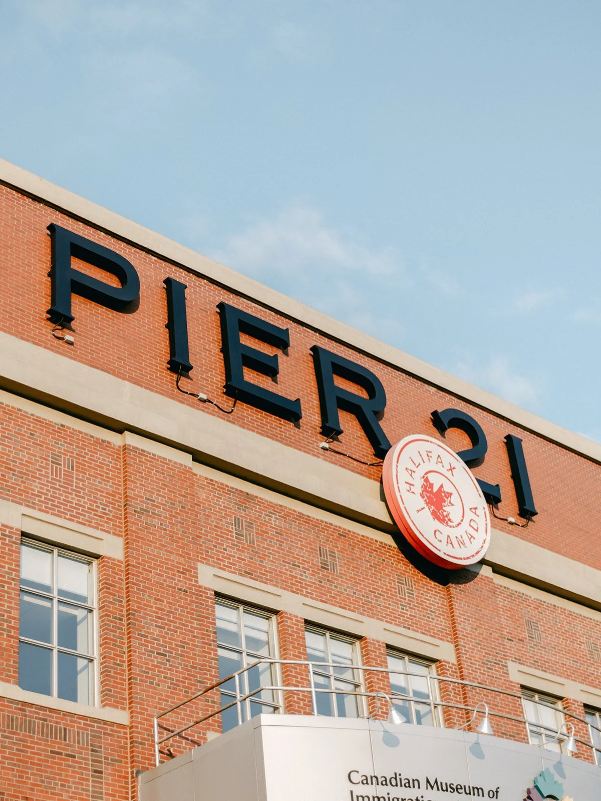 Exterior view of Pier 21 building in Halifax, Canada, with reddish brick walls and a sign for the Canadian Museum of Immigration.