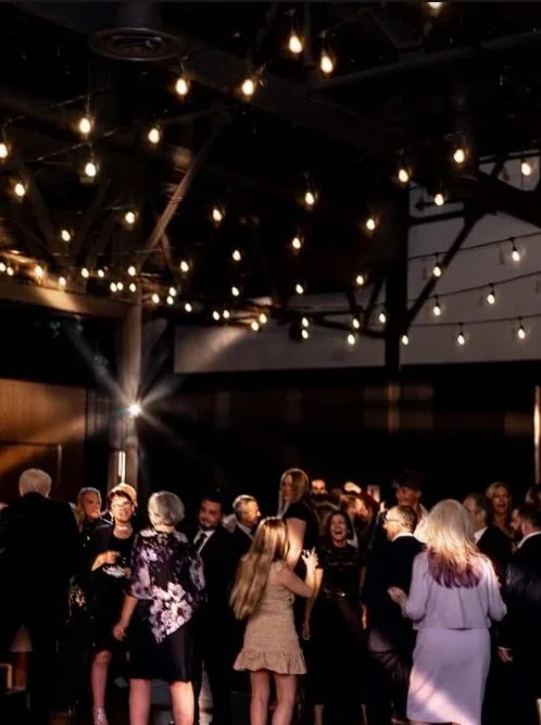 Group of people dancing under string lights at a party