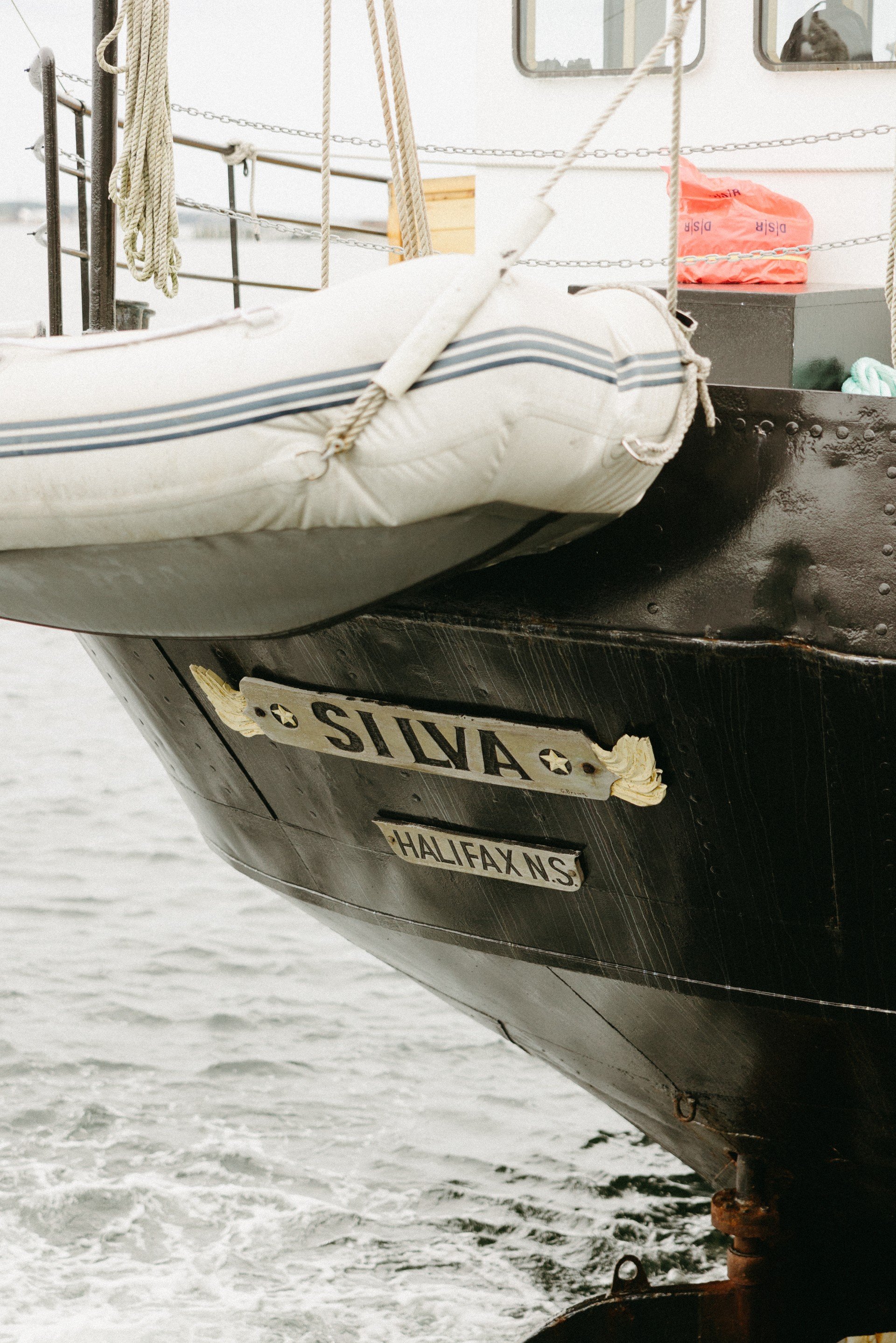 Close-up of a boat named "Silva" with "Halifax N.S." text, showing part of the hull, a lifeboat, and safety equipment on deck.