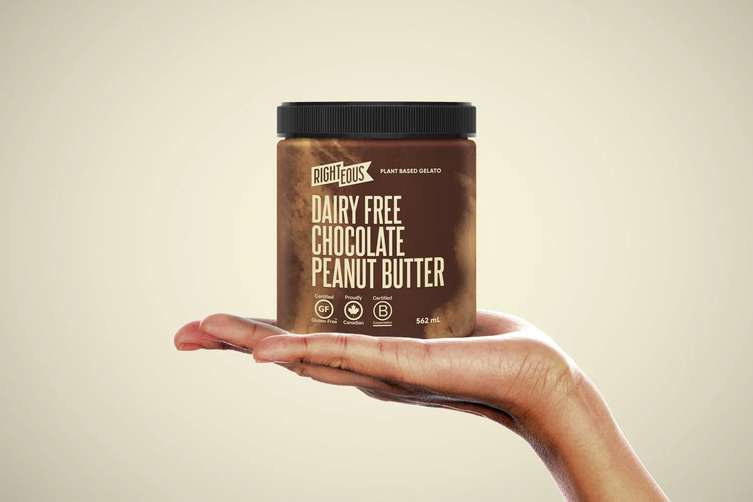 Hand holding a jar of Rightteous dairy free chocolate peanut butter, with a beige background.