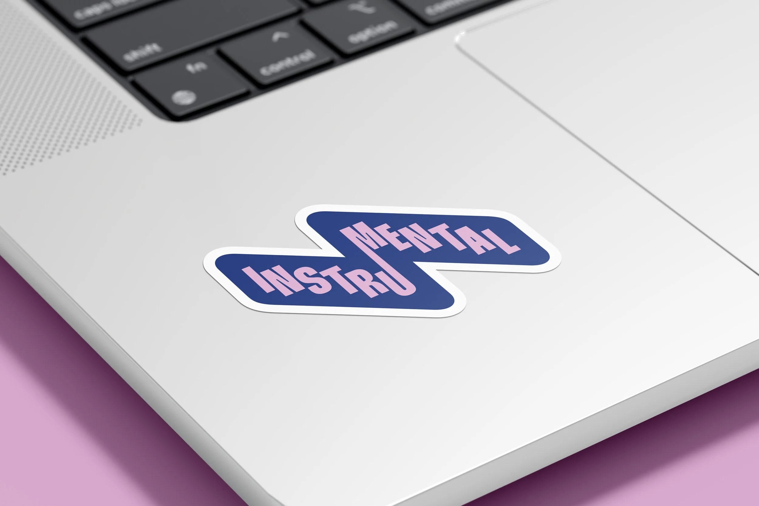 Sticker with the word 'INSTITIAL DIGITAL' on a white desk near a laptop keyboard with pink background.