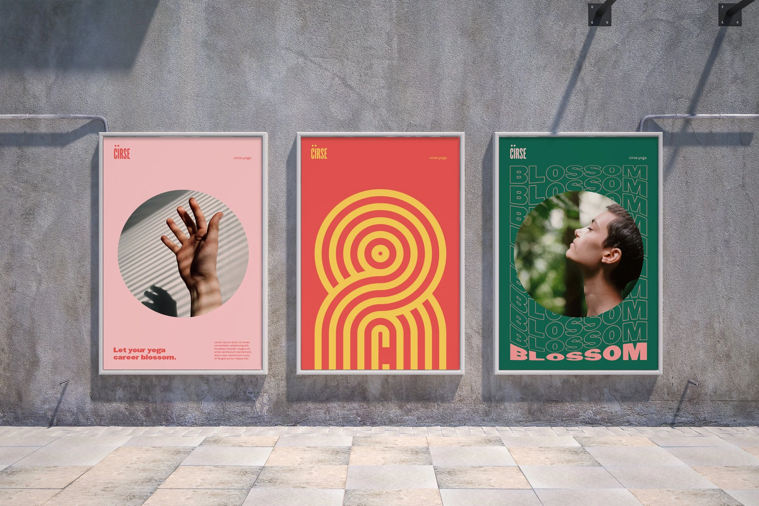 Three posters on a gray wall. The first poster shows a hand reaching upward with shadows and lines running across it, on a pink background, with the text "Let your yoga career blossom." The second poster features a yellow maze-like spiral on a red ba