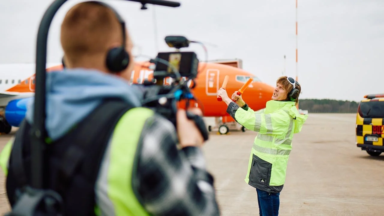 Ein Mann erklärt beim Flughafen ein Flugzeug, während ein Kamerateam ihn filmt. mila motions Werbefilmproduktion