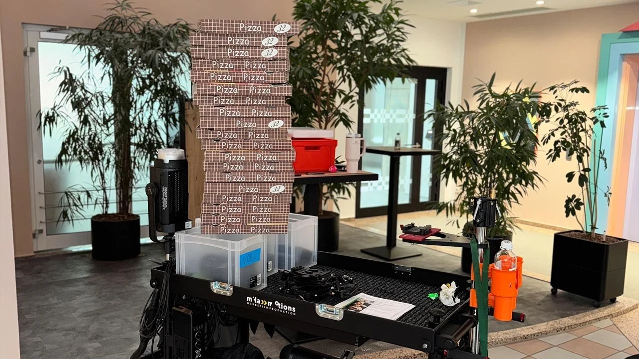 Ein Kamerawagen auf dem Pizzakartons liegen, die als Requisiten dienen. in einem Raum mit Pflanzen. mila motions Werbefilmproduktion