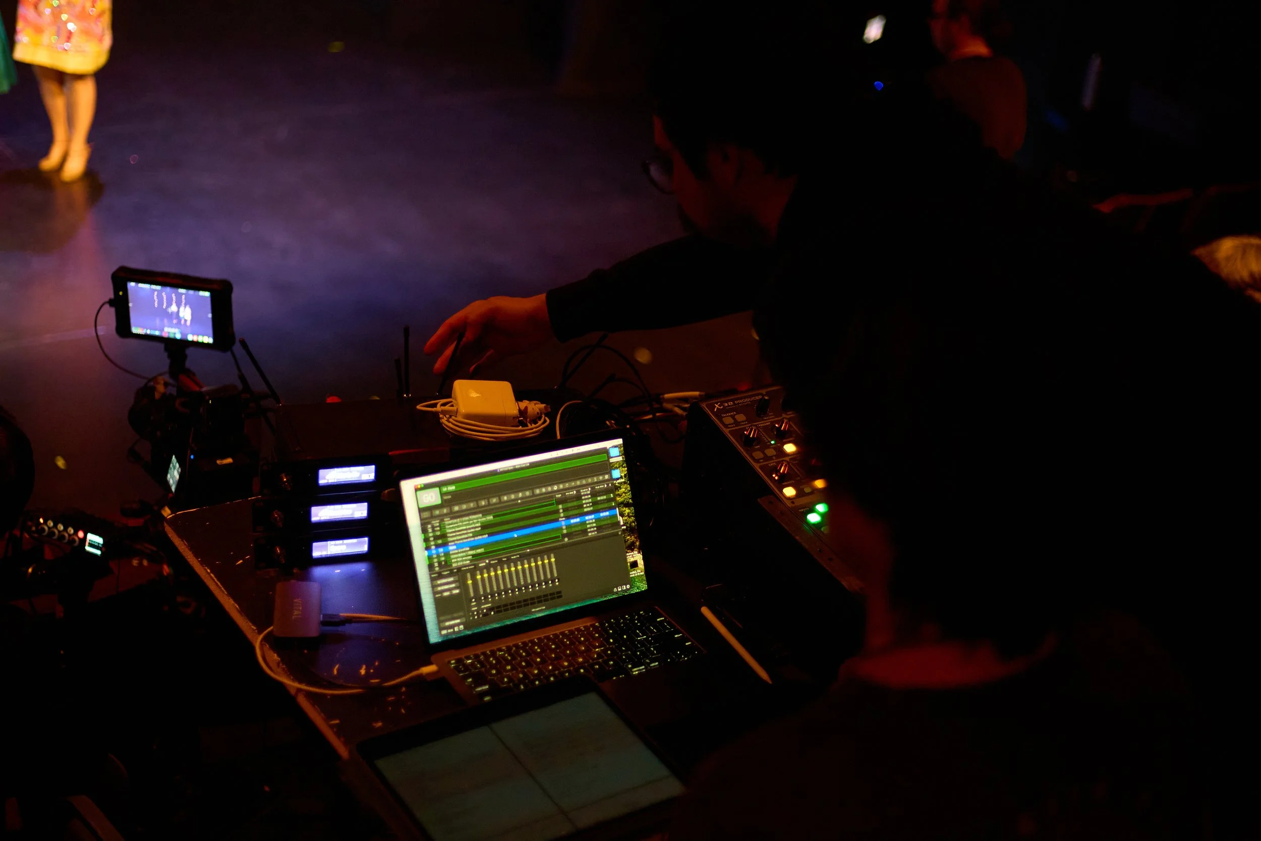 Technicien en sonorisation ajustant l'équipement lors d'une soirée dans une pièce sombre.