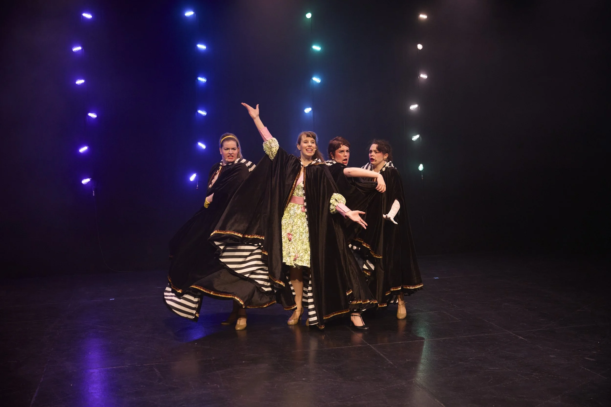 Créations In Vivo. Cinq jeunes femmes dans des costumes de théâtre sur scène, faisant une performance théâtrale lors d'une représentation.