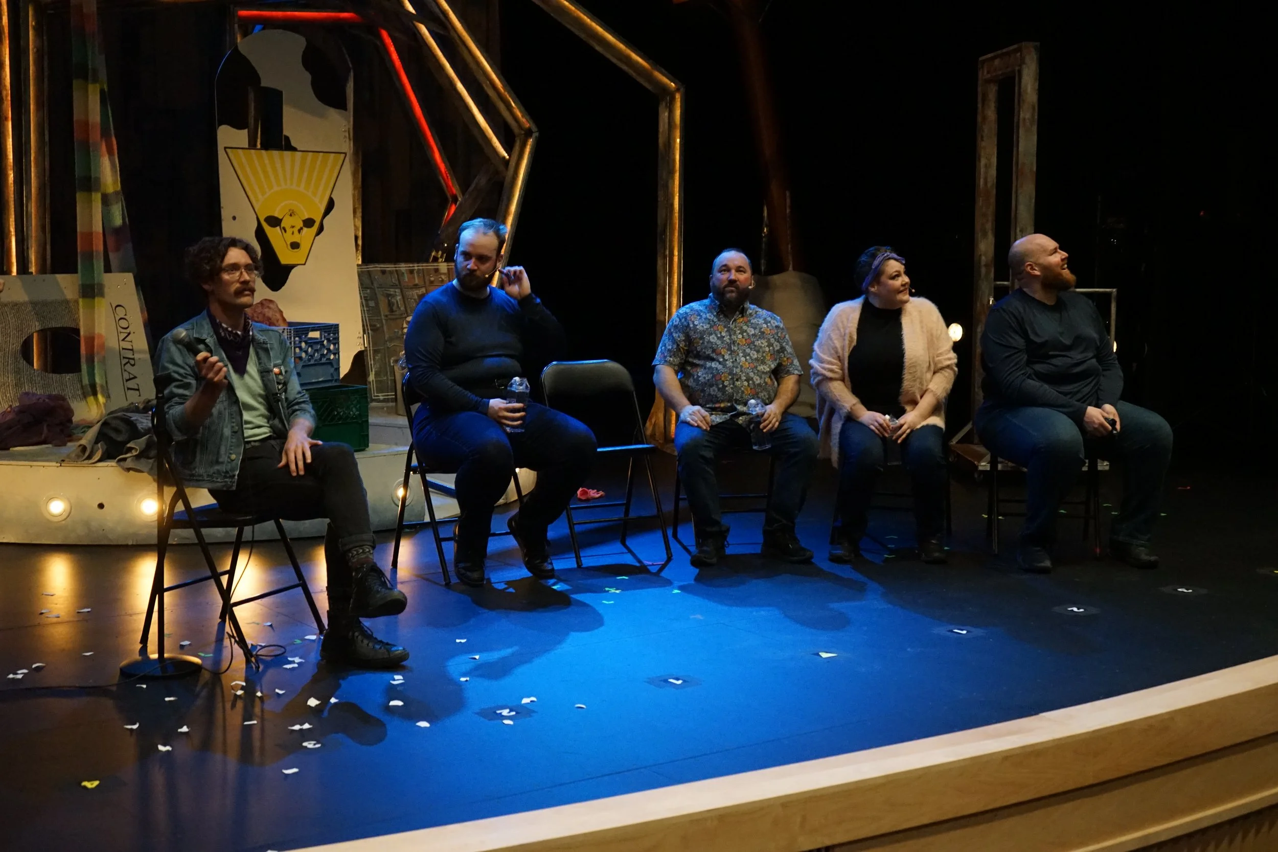 Cinq personnes assises sur scène lors d'une discussion ou d'un panel, avec un décor artistique en arrière-plan.