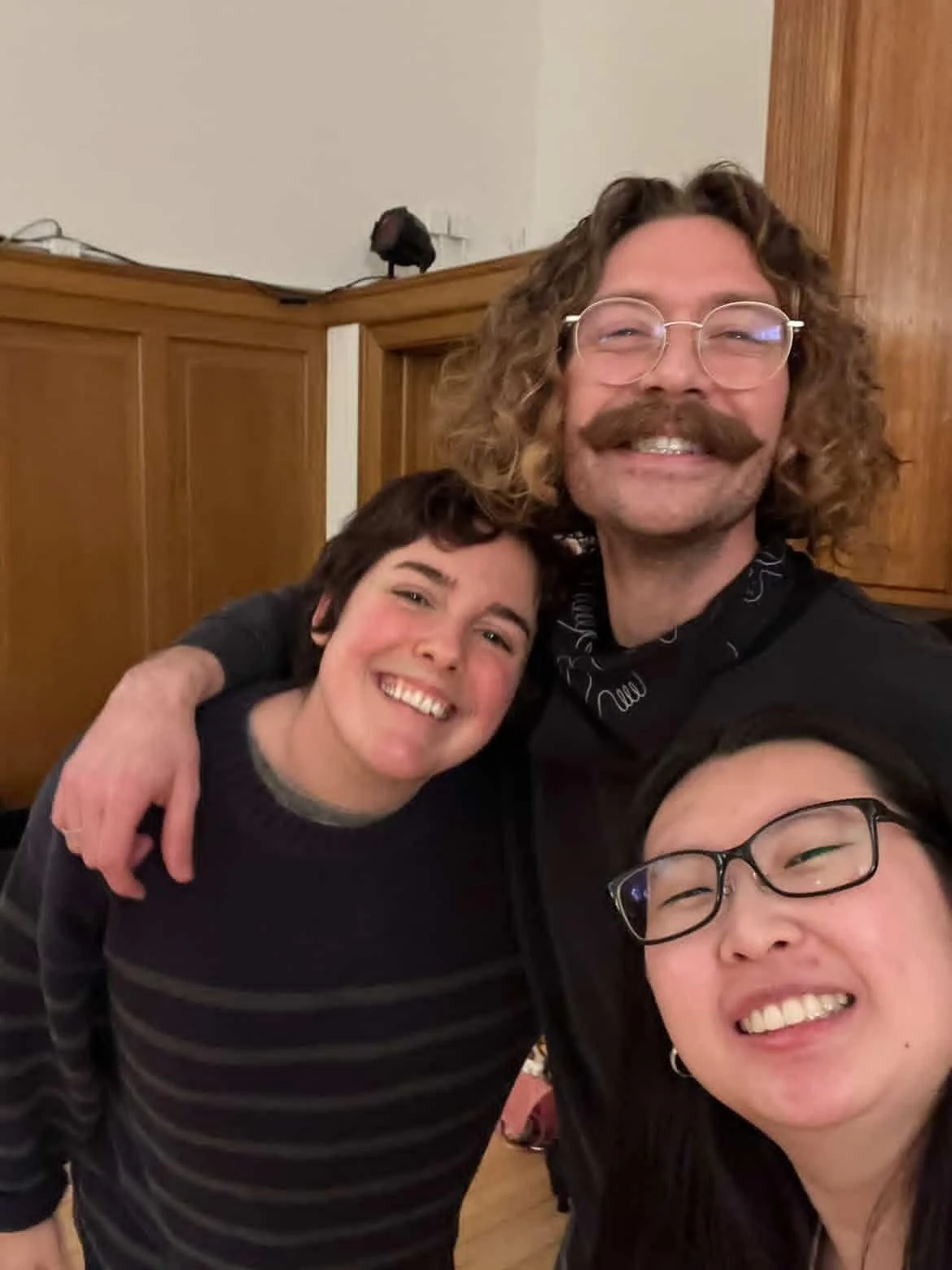 Créations In Vivo. Trois personnes souriantes posant pour une photo dans une pièce avec des murs en bois.