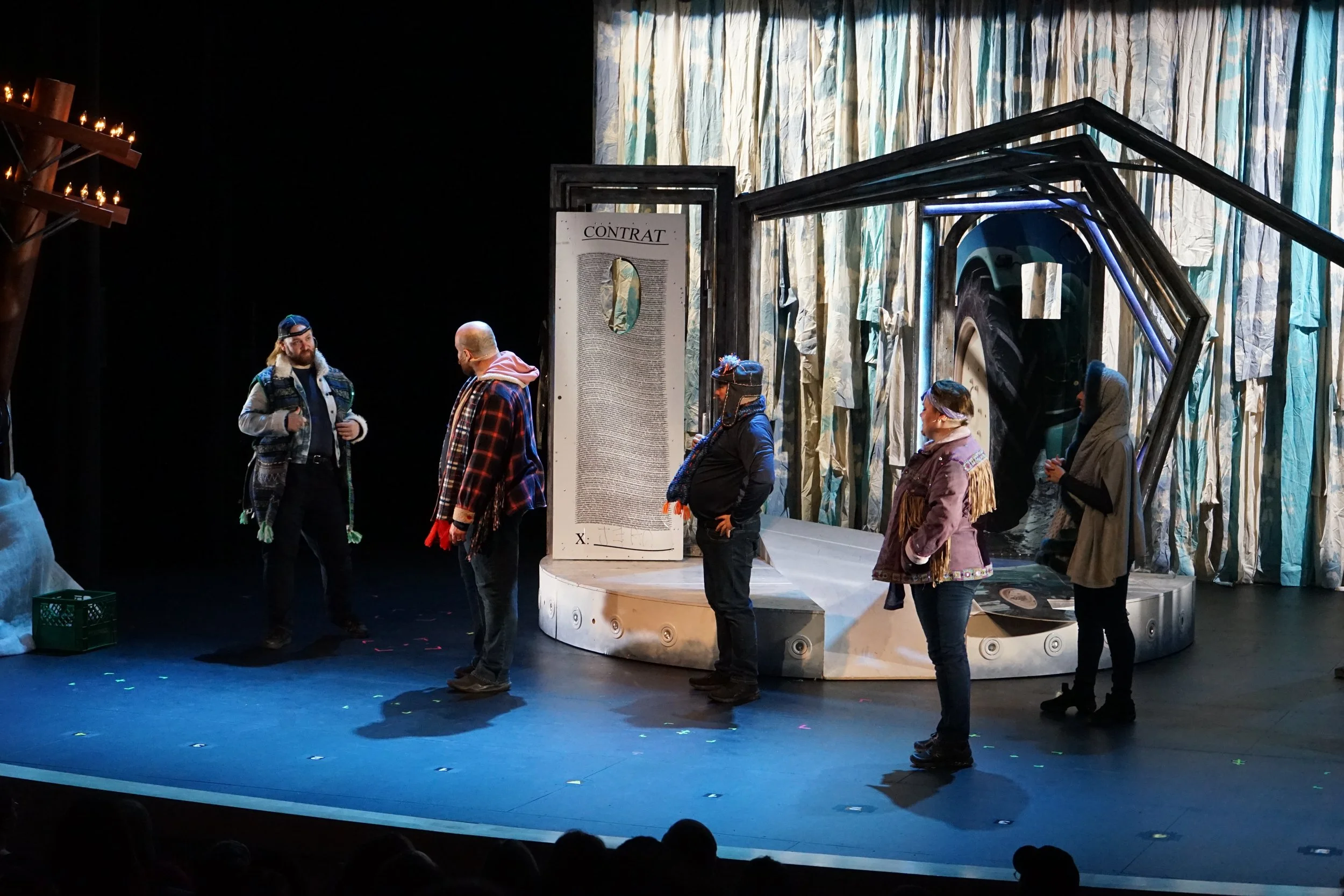 Cinq personnes sur scène dans un théâtre, dialogue en pleine représentation.