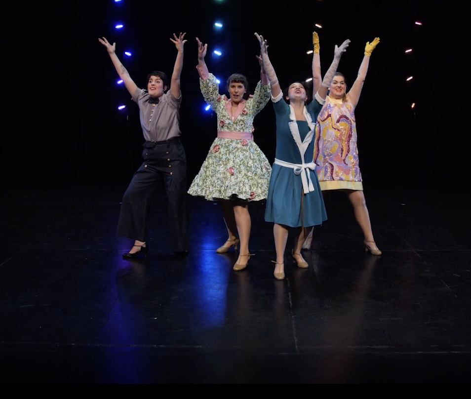 Groupe de cinq personnes en costume de théâtre sur scène, posant avec expressions expressives, ambiance de spectacle, éclairage dramatique.