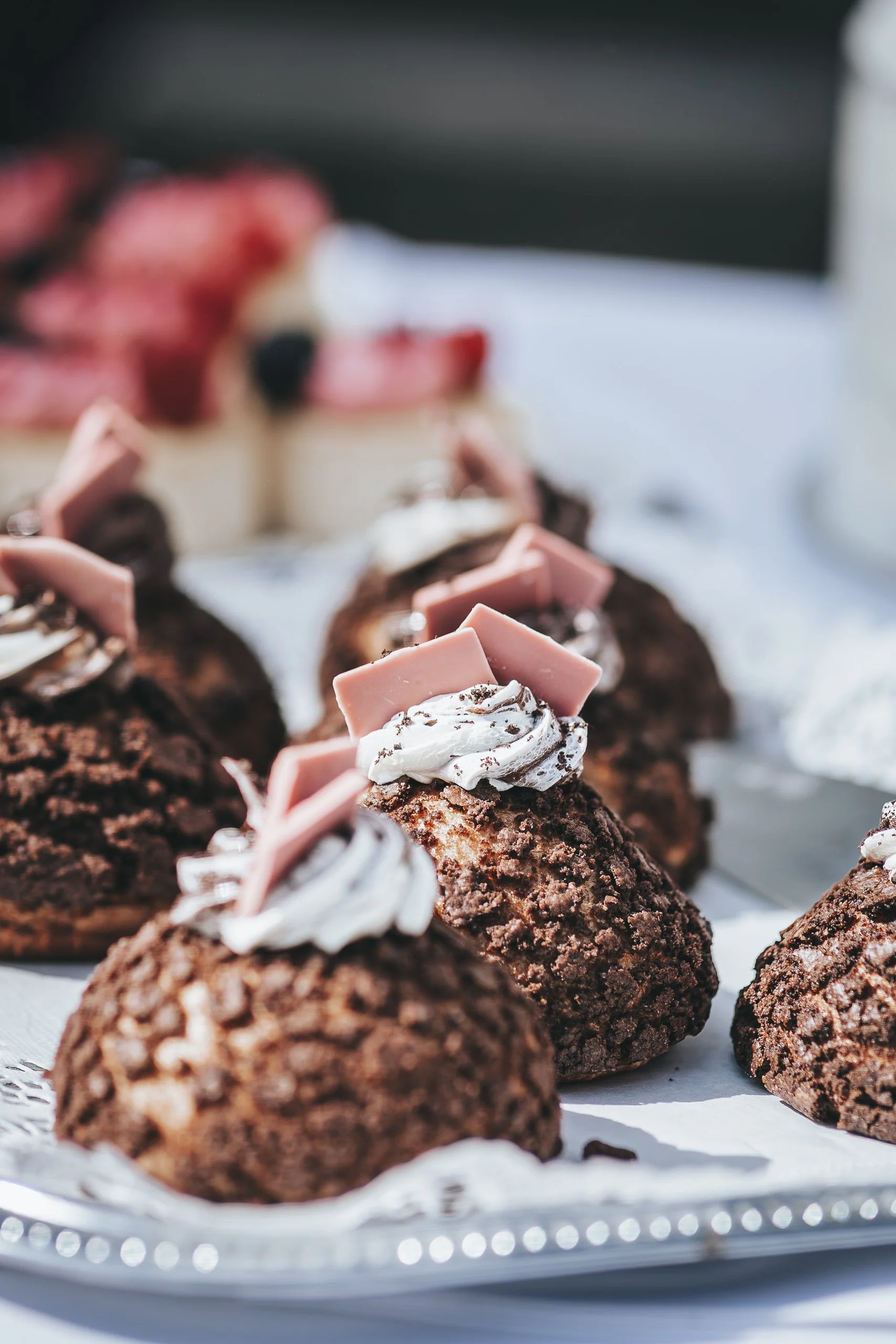 Nahaufnahme von Schokoladekugeln mit Sahne, Schokoladenspänen und pinkem Schokolade auf einer silbernen Servierplatte.