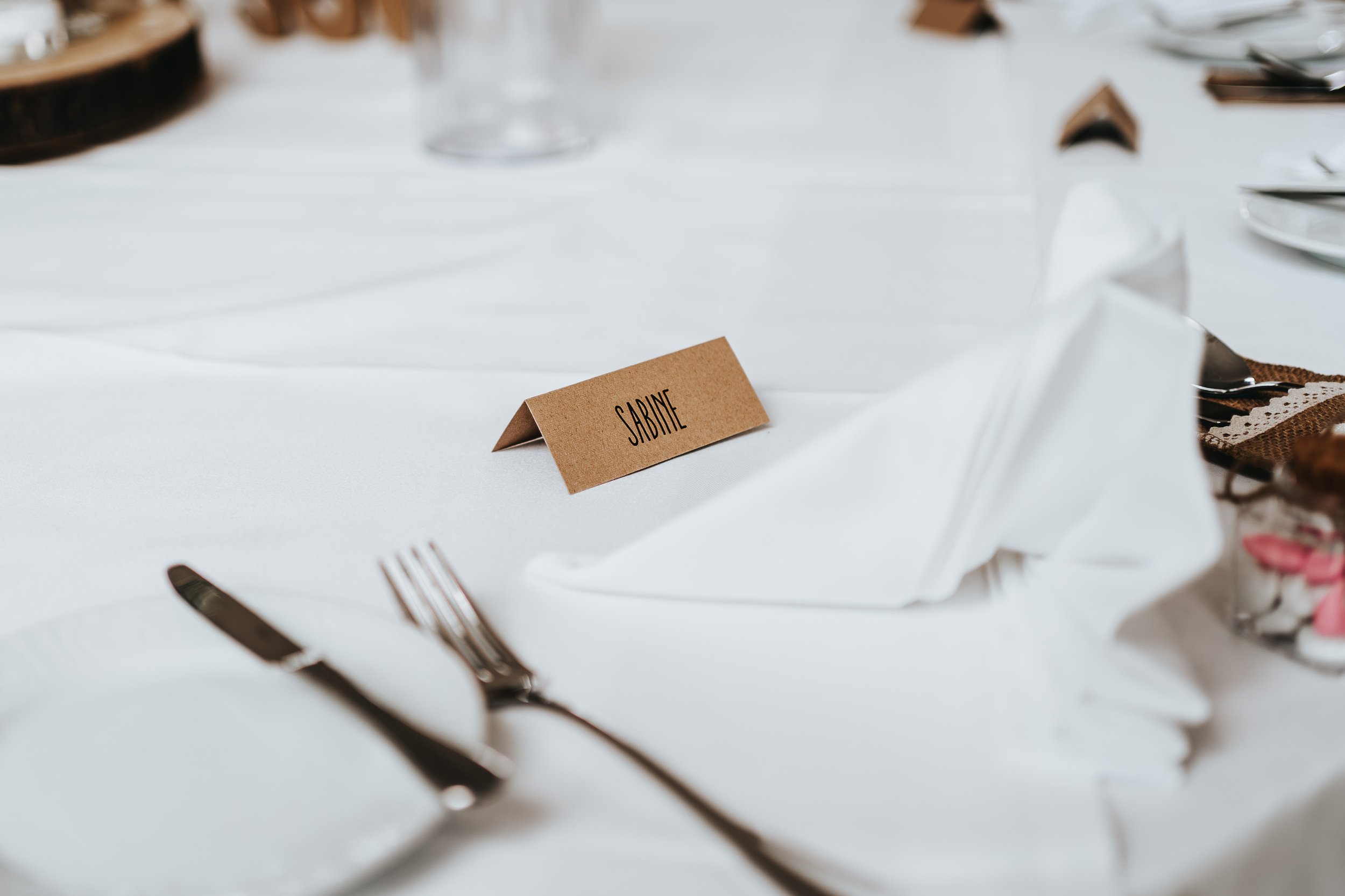 Ein schön gedeckter Tisch bei einer Hochzeit mit einem Platzkarte mit dem Namen 'SABINE'.