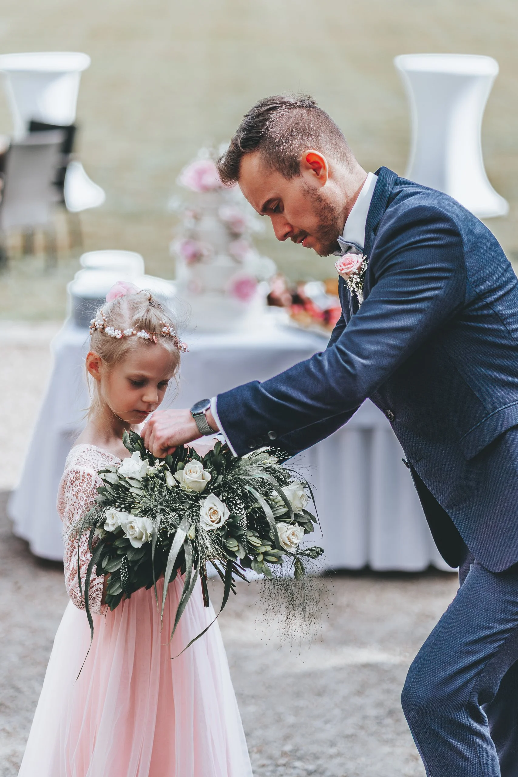 Ein Mann im Anzug übergibt einem Mädchen ein Blumenstrauß bei einer Hochzeit im Freien.